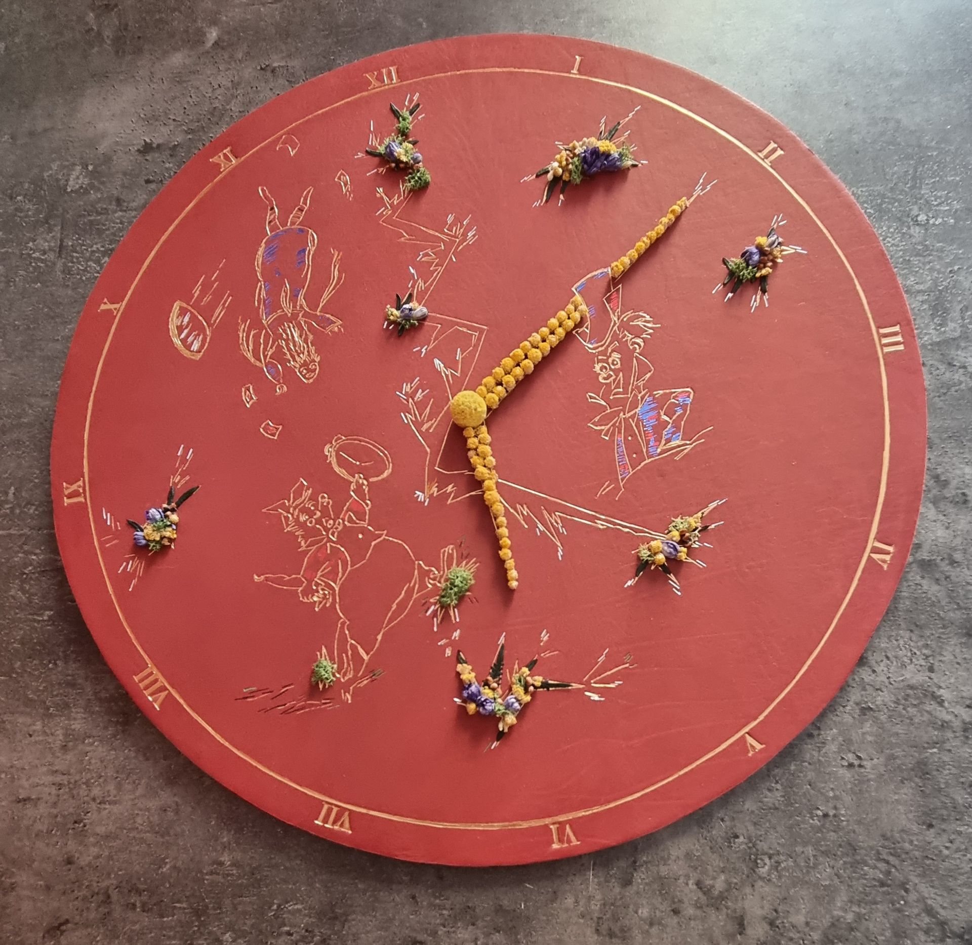 Une horloge rouge avec des chiffres romains et des fleurs dessus