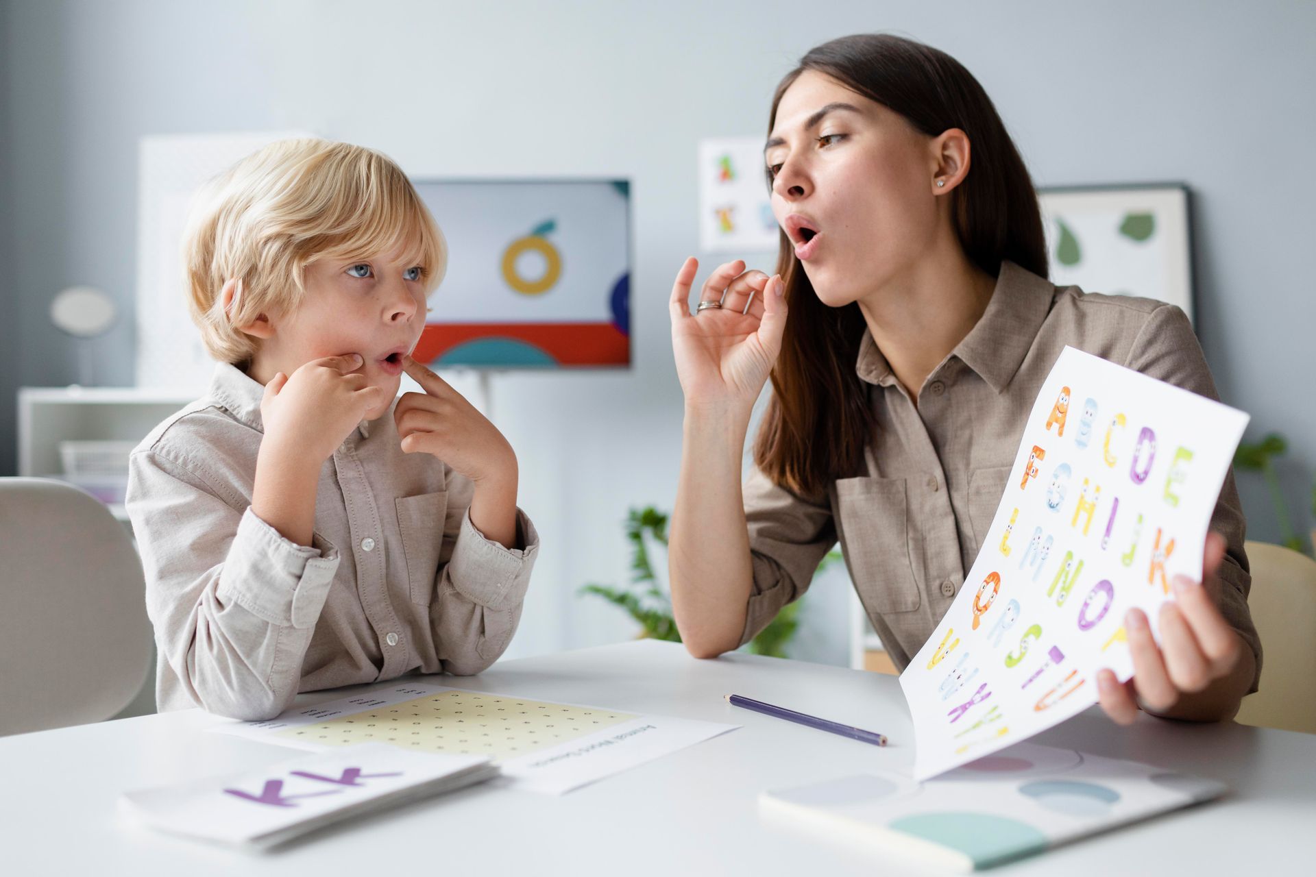 Two people at a table practicing speech sounds with flashcards and worksheets