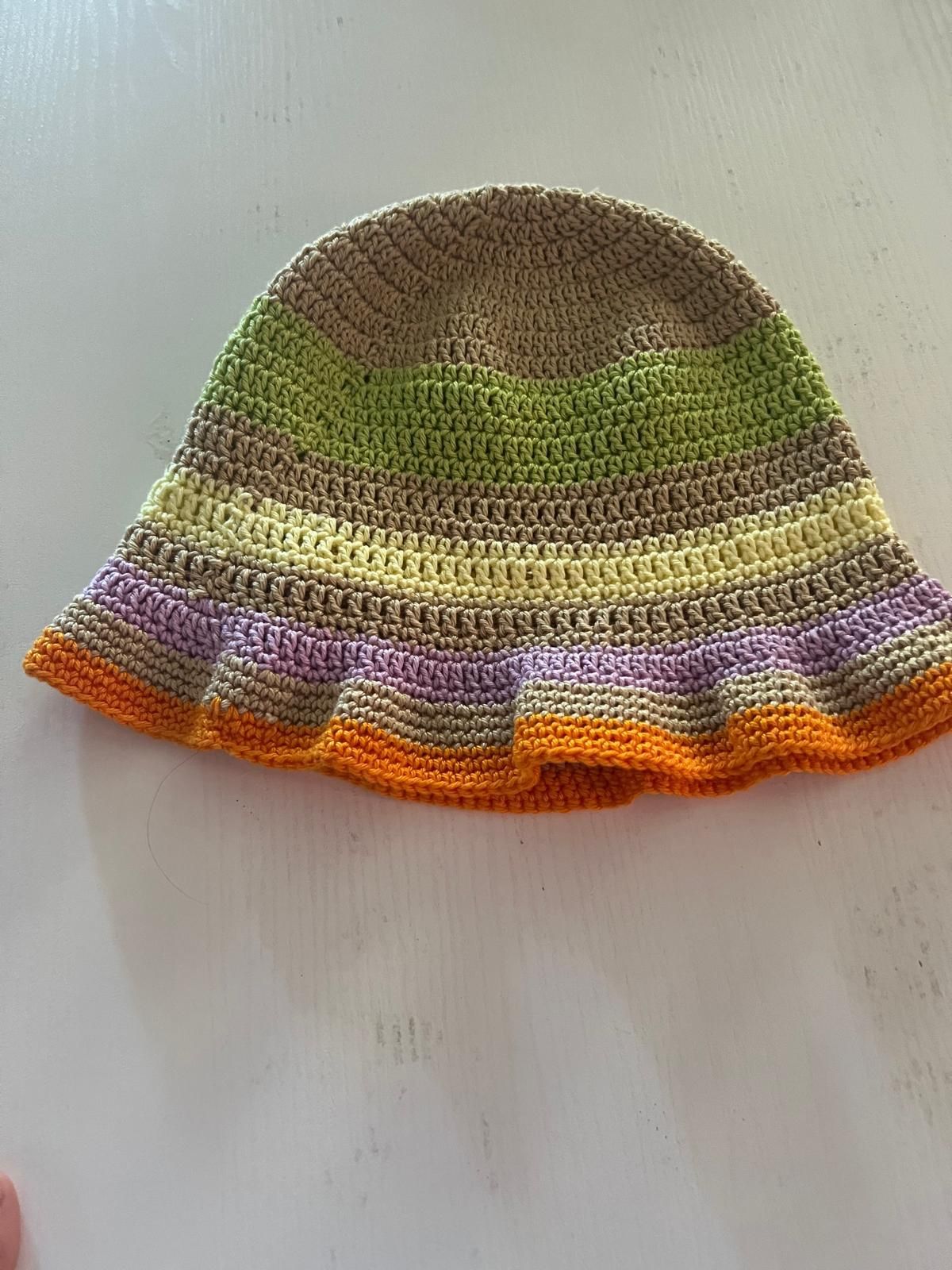 Berretto lavorato a maglia a righe multicolore con fasce marroni, verdi, viola e arancioni su sfondo chiaro