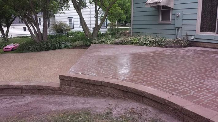 A brick patio with a brick wall in front of a house.