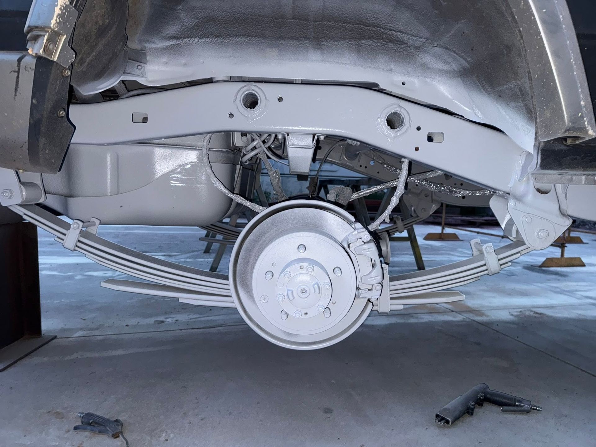 Car’s undercarriage with exposed rear suspension and a wheel removed in a garage