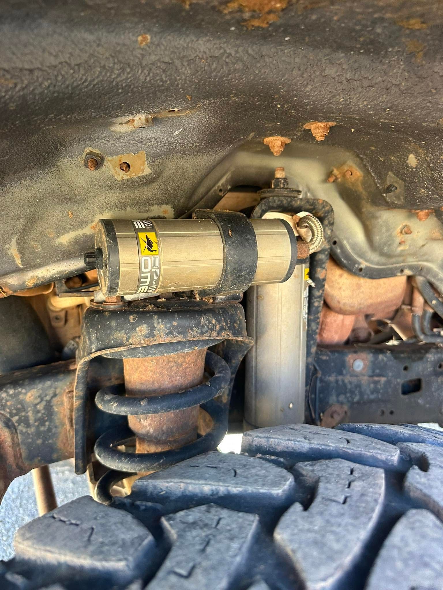 Close-up of a vehicle’s suspension and wheel well with a visible shock absorber and coil spring