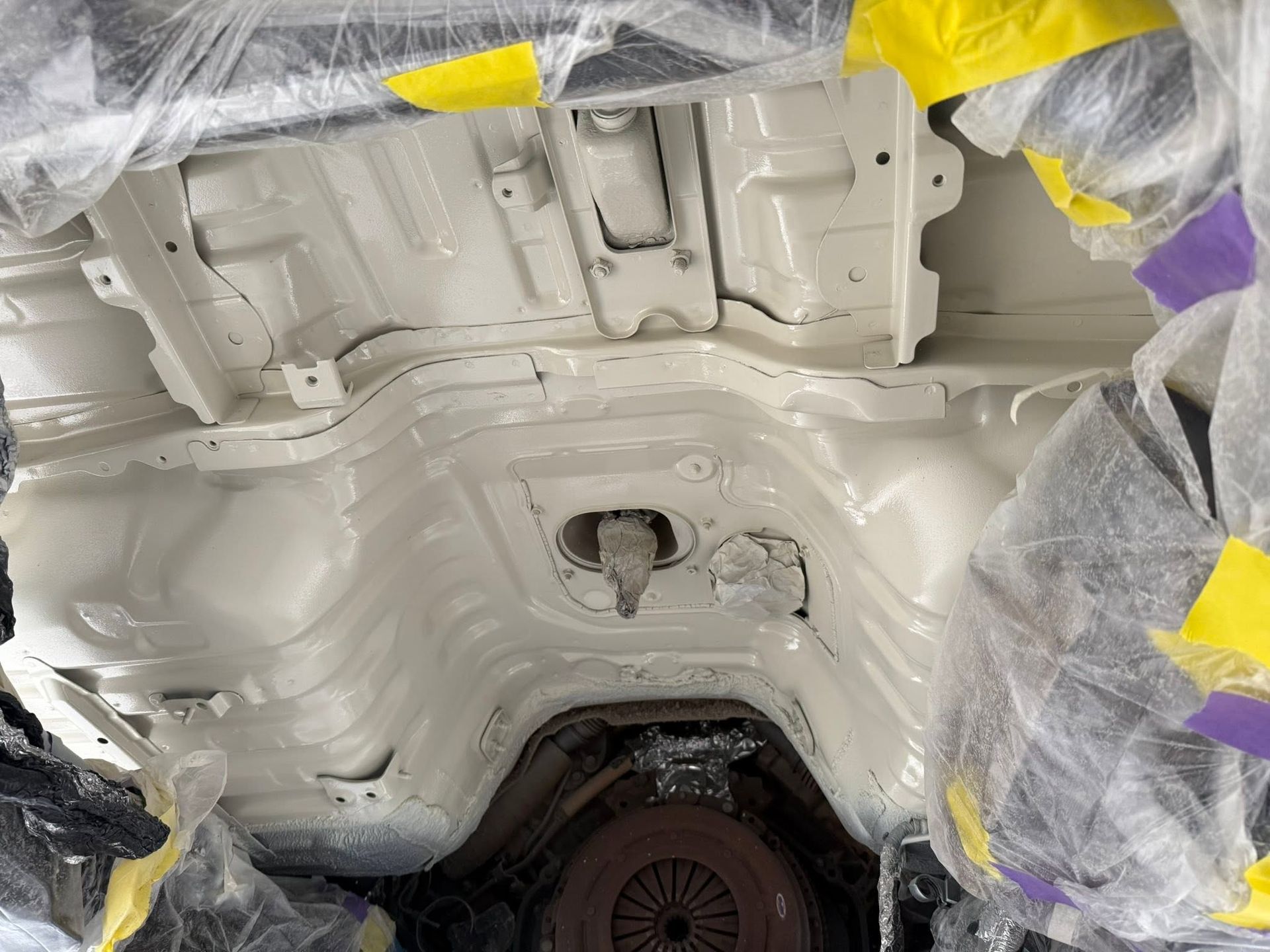 White-painted car underbody with masking tape and plastic covering during paint or repair work