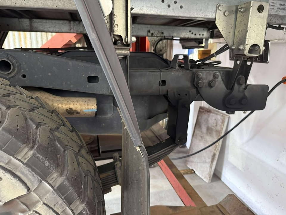 Undercarriage of a truck showing suspension, axle, and tire in a workshop garage