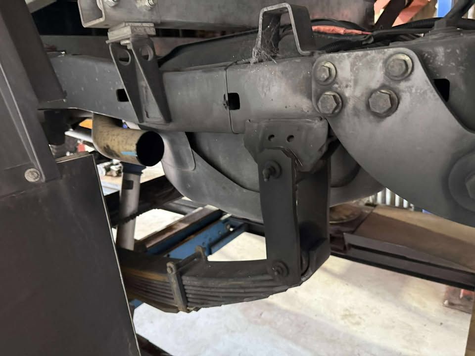 Close-up of a truck’s rear suspension, leaf spring, and axle components under the chassis