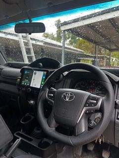 Toyota car interior with steering wheel, dashboard, and a phone mounted near the center console in a rainy setting