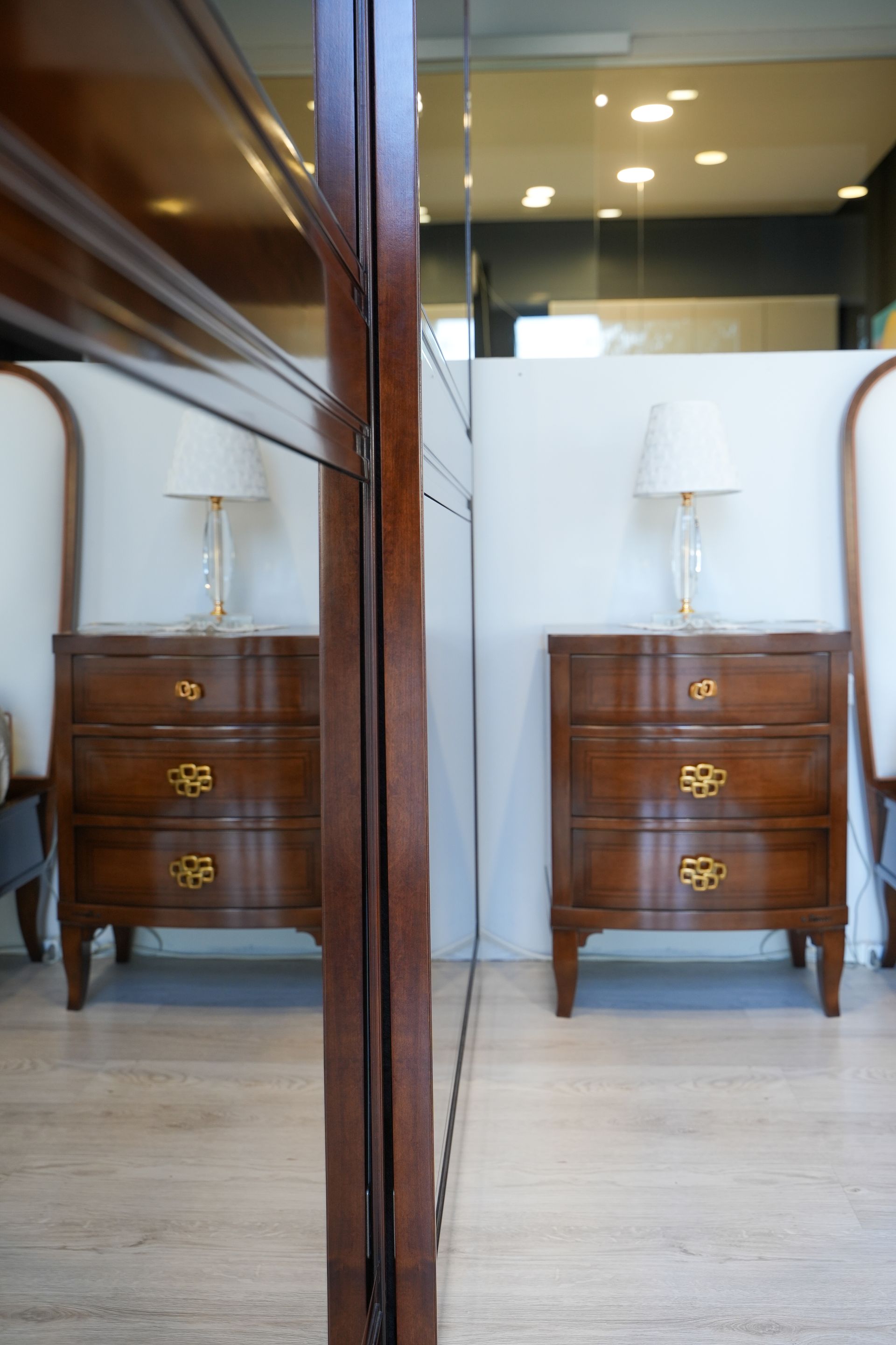 Due cassettiere di legno con lampade sopra davanti a uno specchio