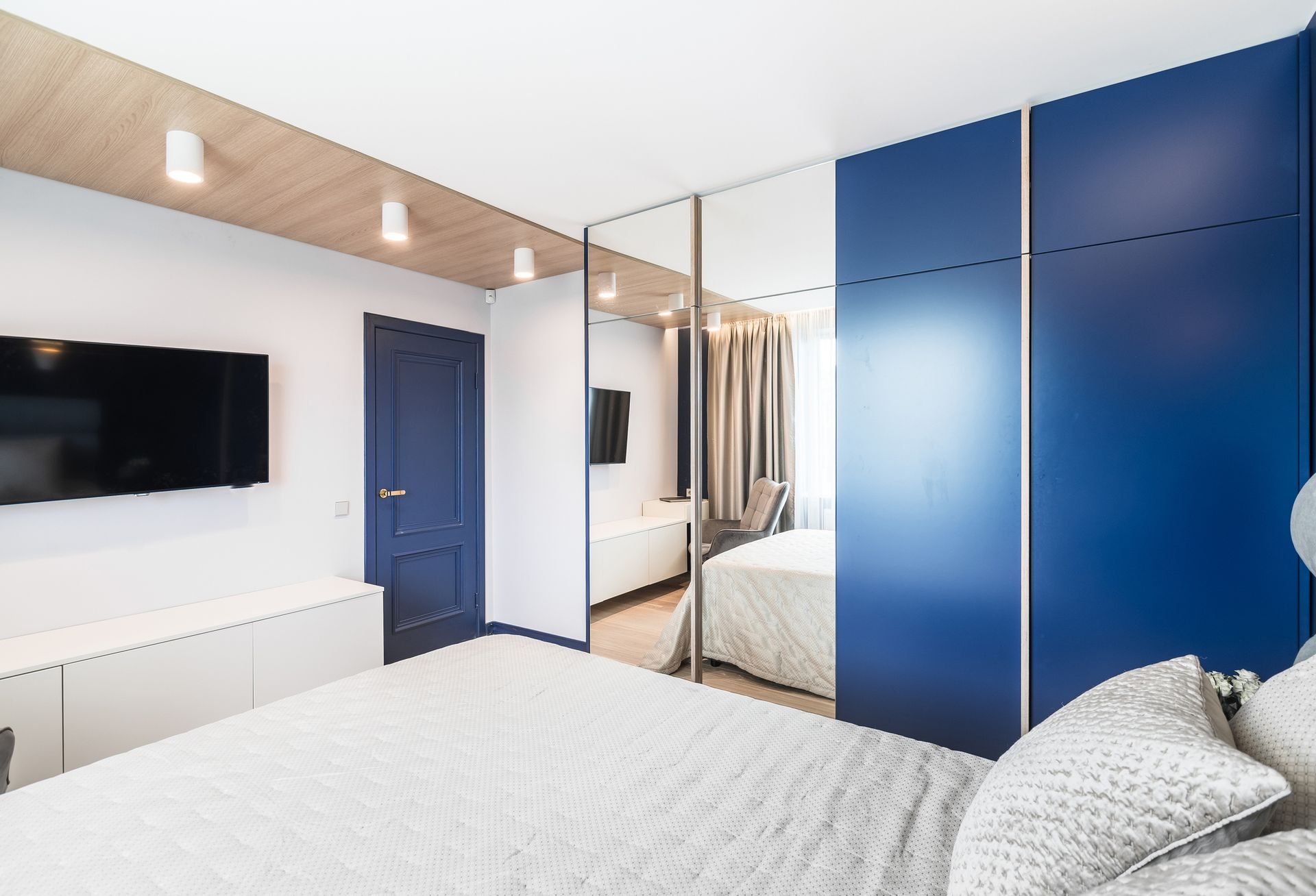 Una camera da letto con un letto, una televisione e pareti blu.