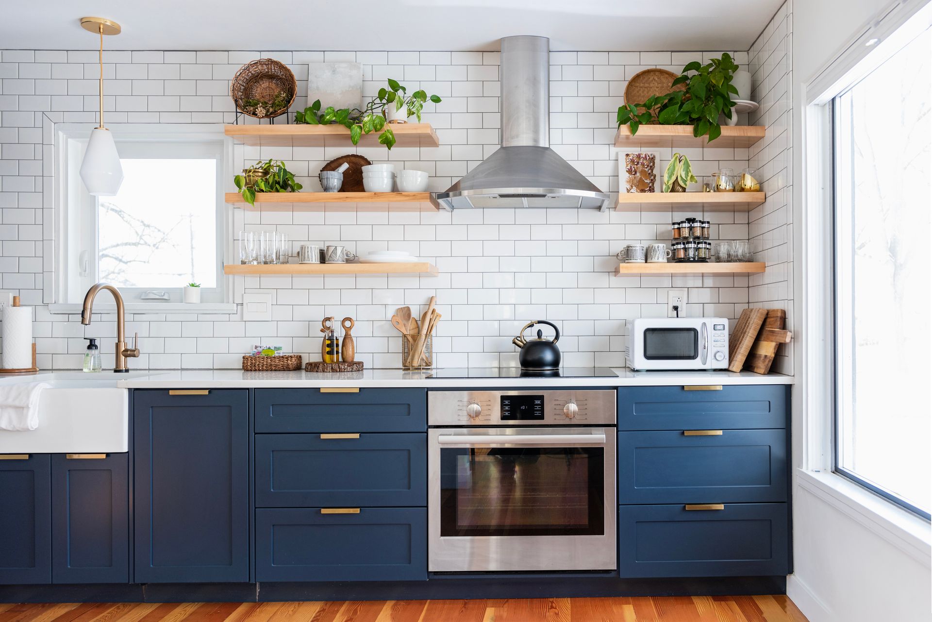 Una cucina con mobili blu, elettrodomestici in acciaio inossidabile, un lavandino e una finestra.