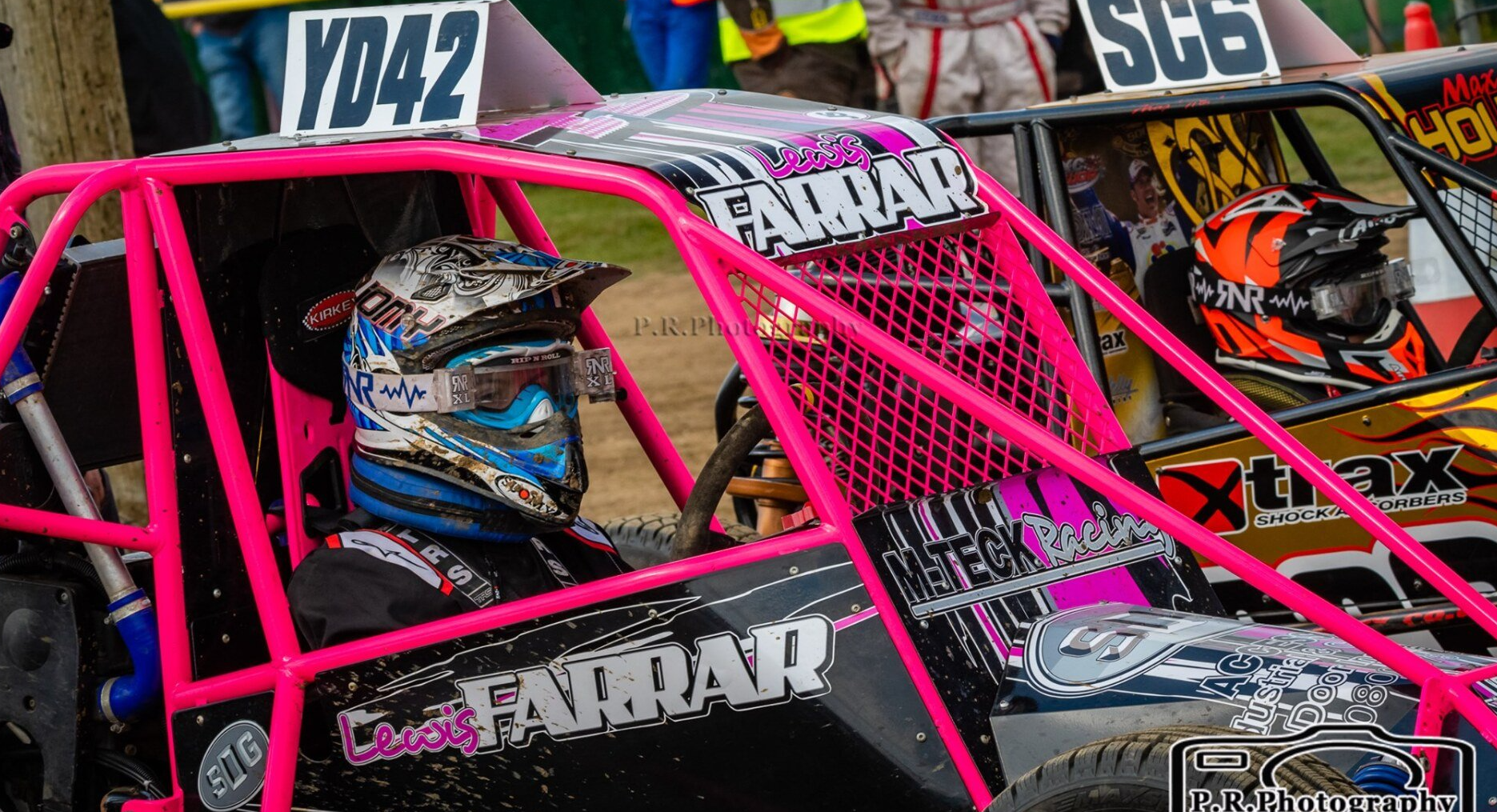 A person is sitting in a pink buggy with a helmet on.
