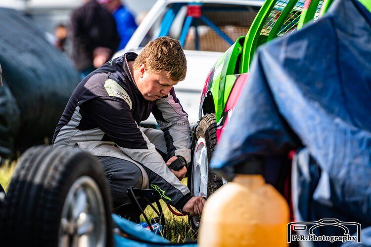 A man is fixing a tire on a race car.