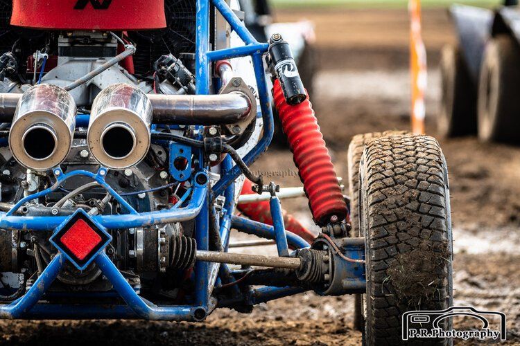 A blue and red buggy is parked in the dirt.