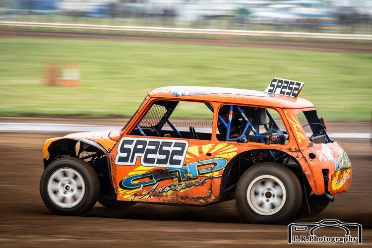 An orange race car with the number sp252 on the side is driving on a dirt track.