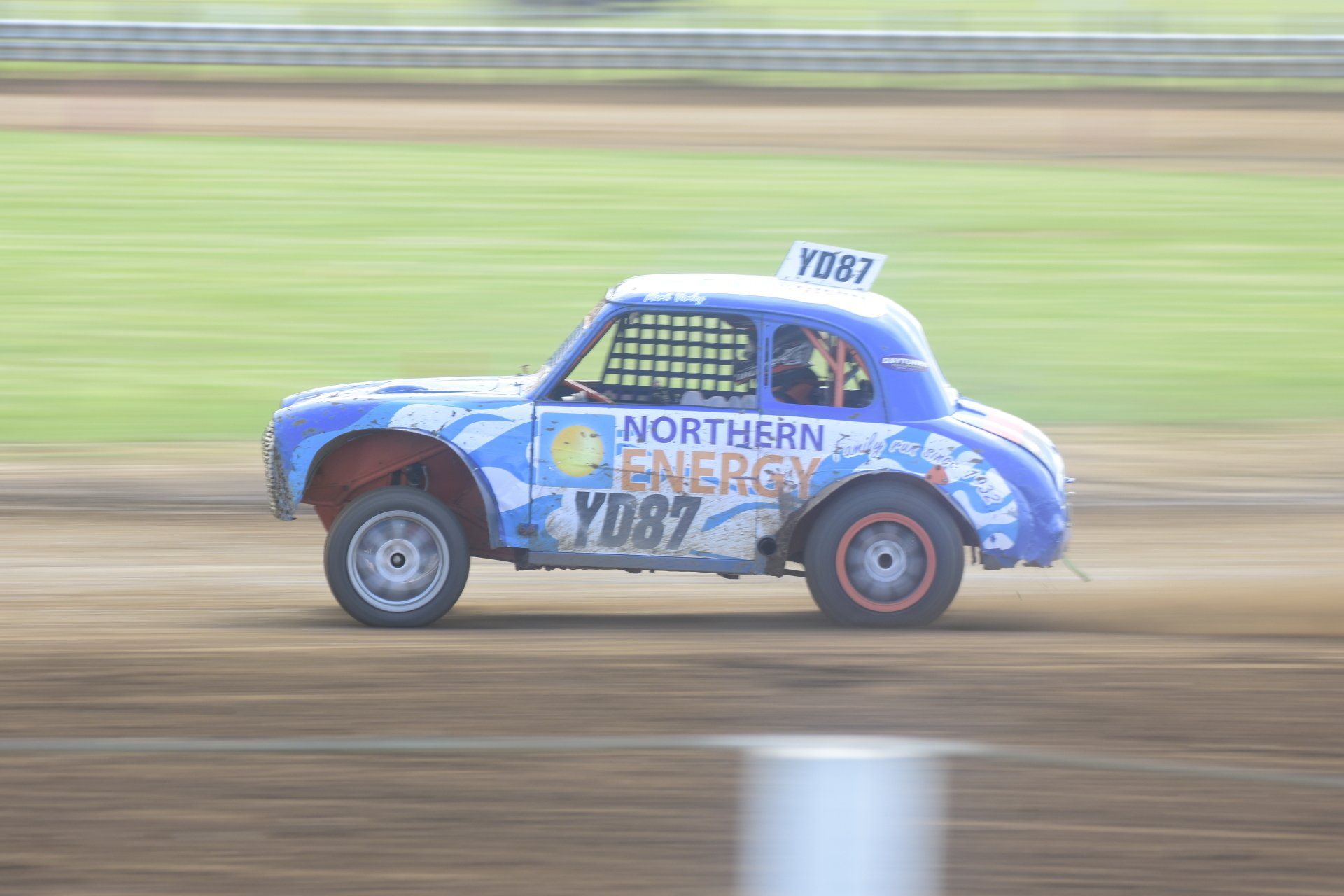 A blue and white race car is driving down a dirt track.