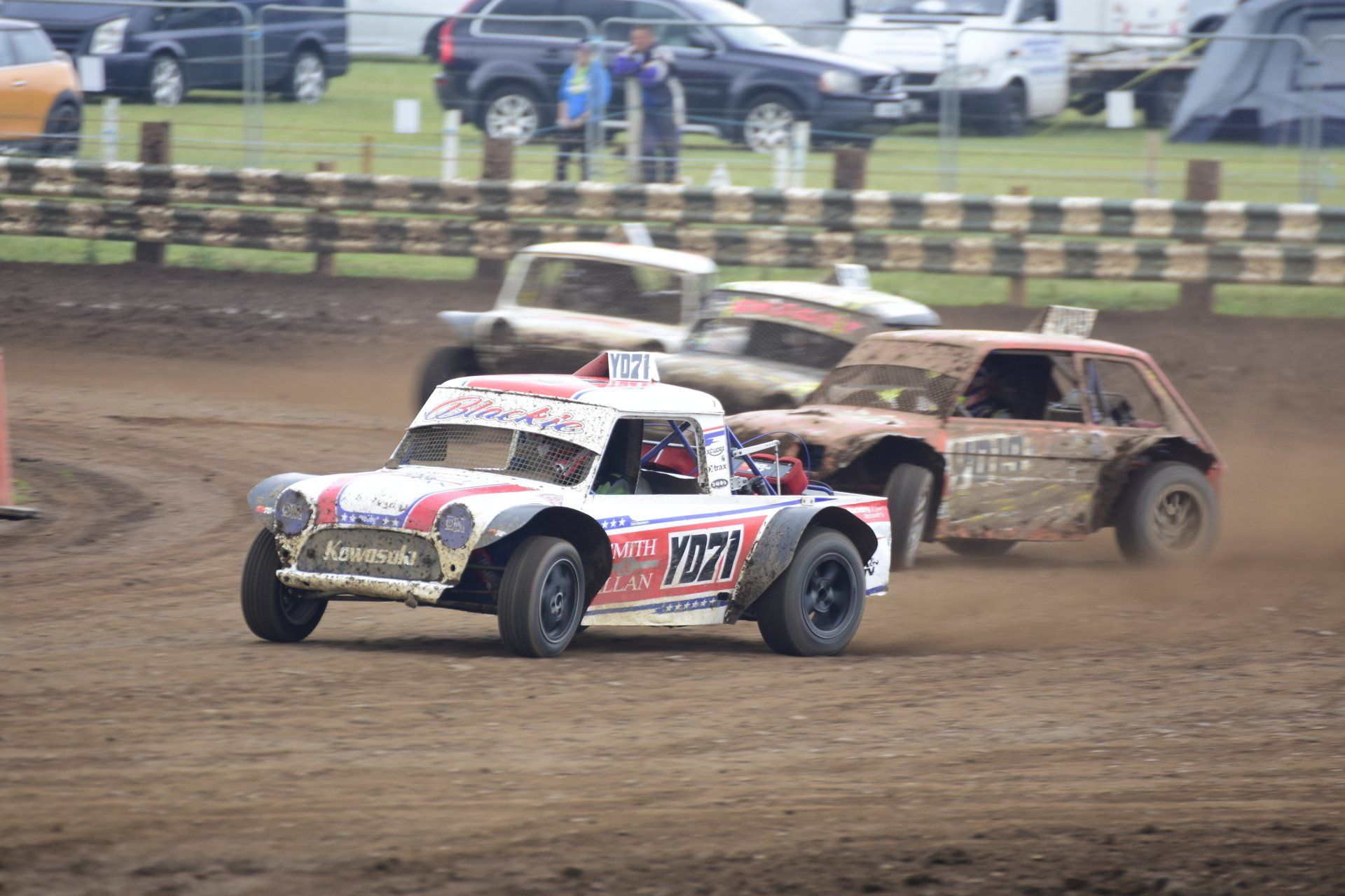 A group of cars are racing on a dirt track.
