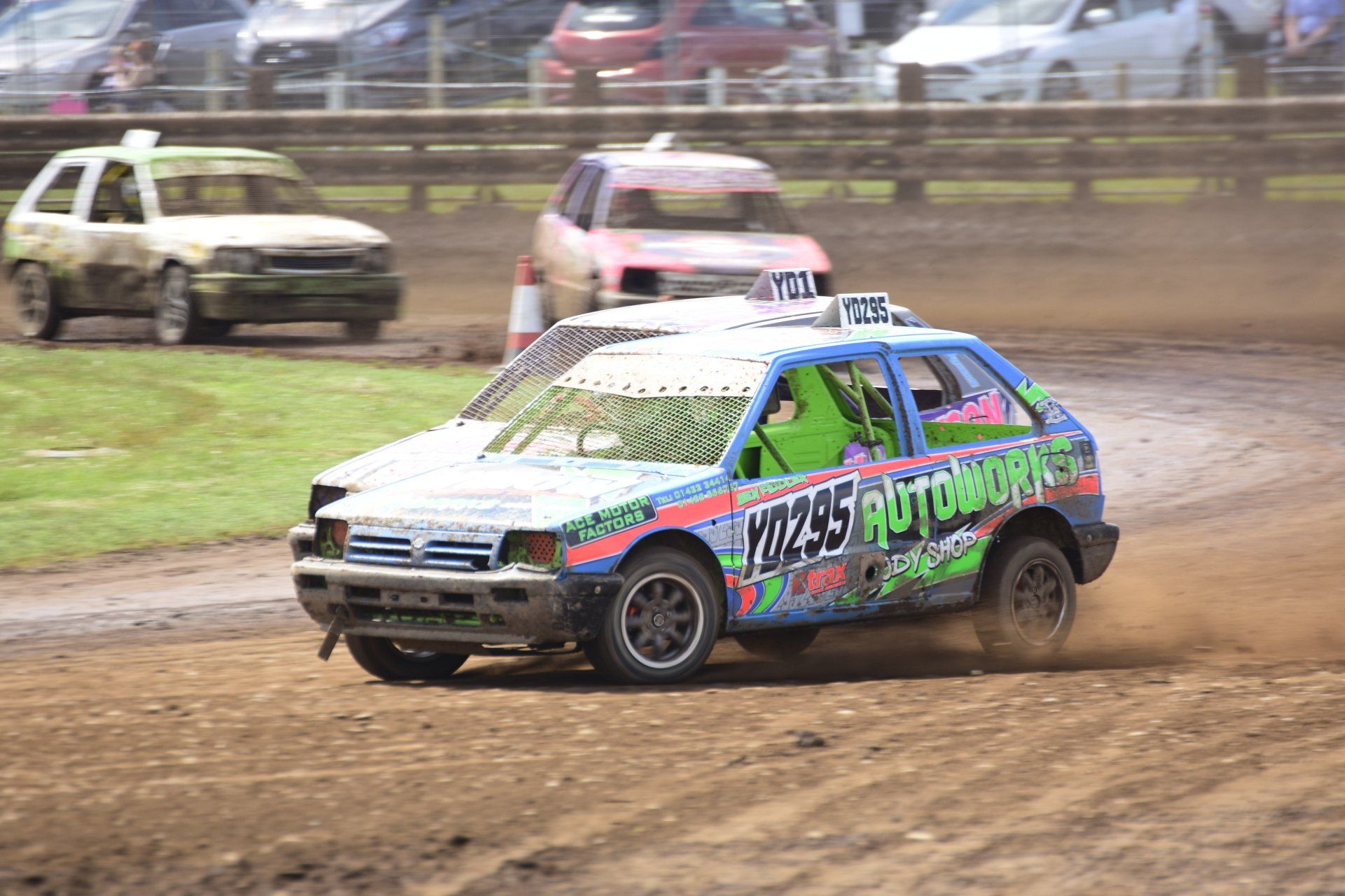 A group of cars are racing on a dirt track.