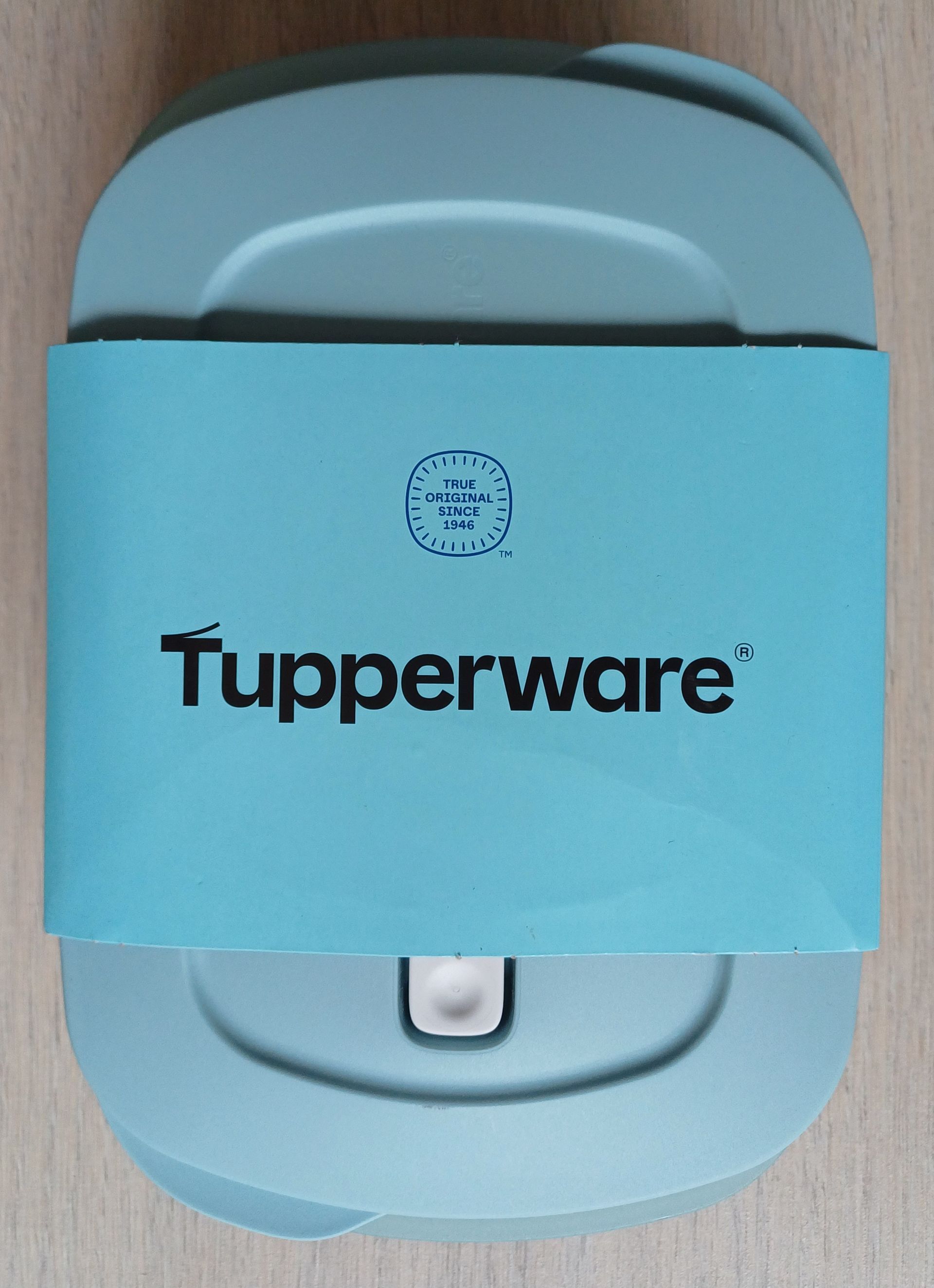 Blauwe Tupperware-bak met een band waarop 
