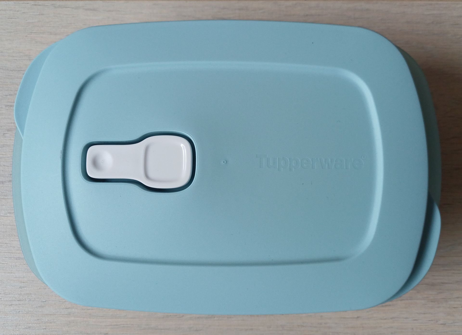 Blauwe Tupperware-bak met een band waarop 