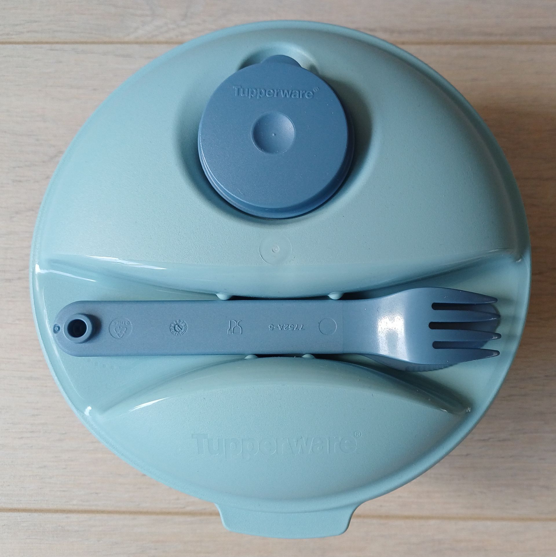 Blauwe Tupperware saladekom met een vork en een klein deksel.