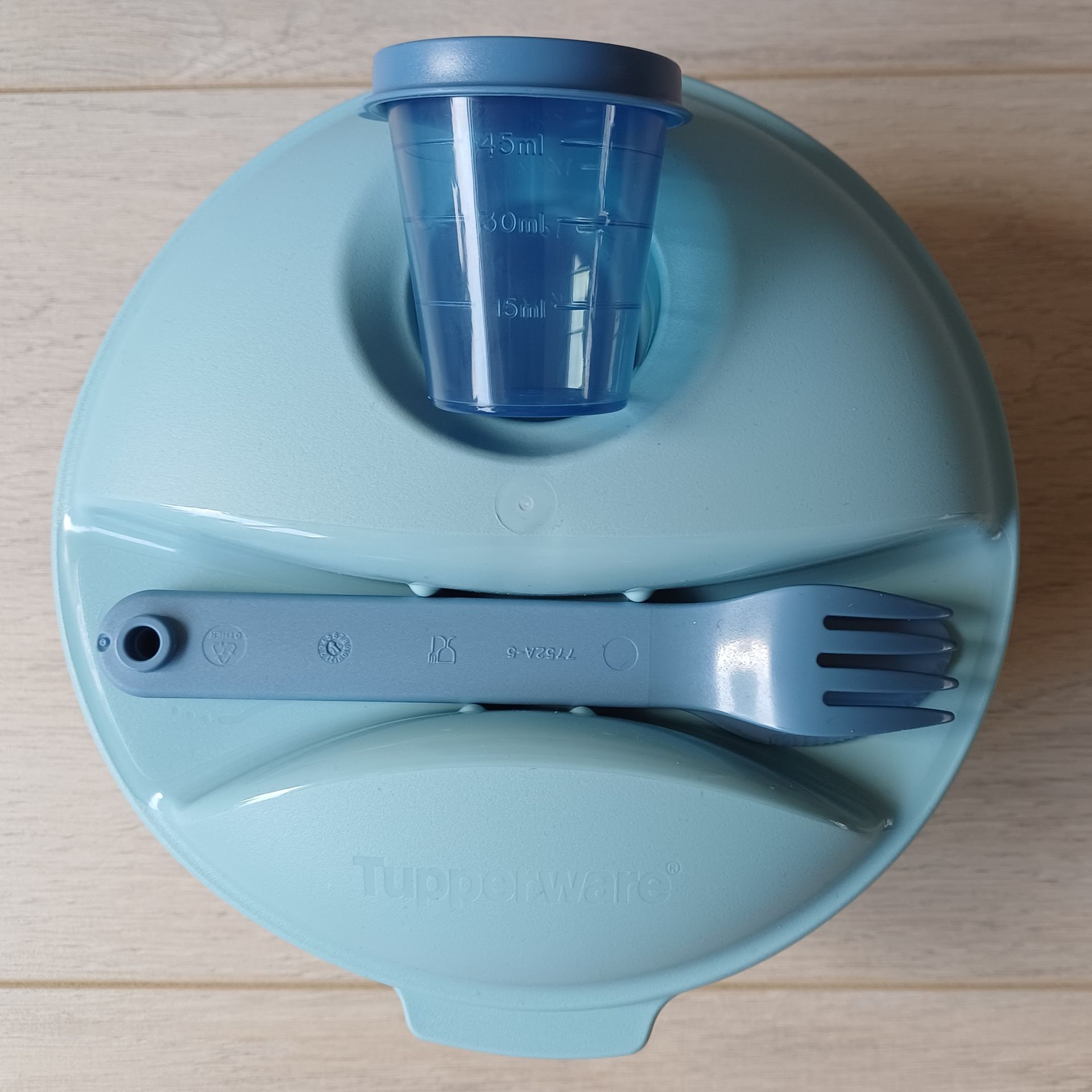 Blauwe Tupperware saladekom met een vork en een klein deksel.