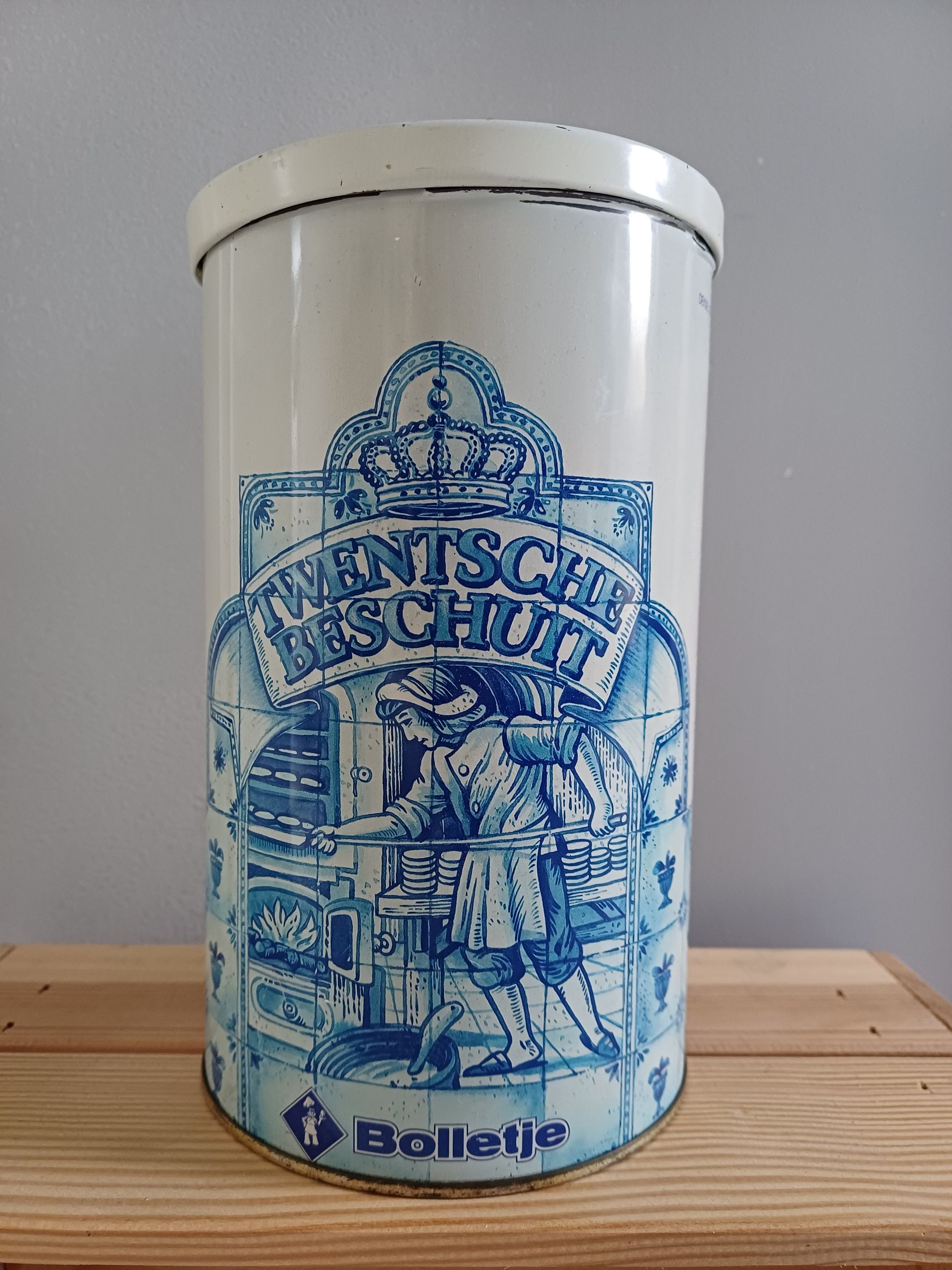 Blauw-witte cilindrische koekjesblik met een bakkersmotief en de tekst 