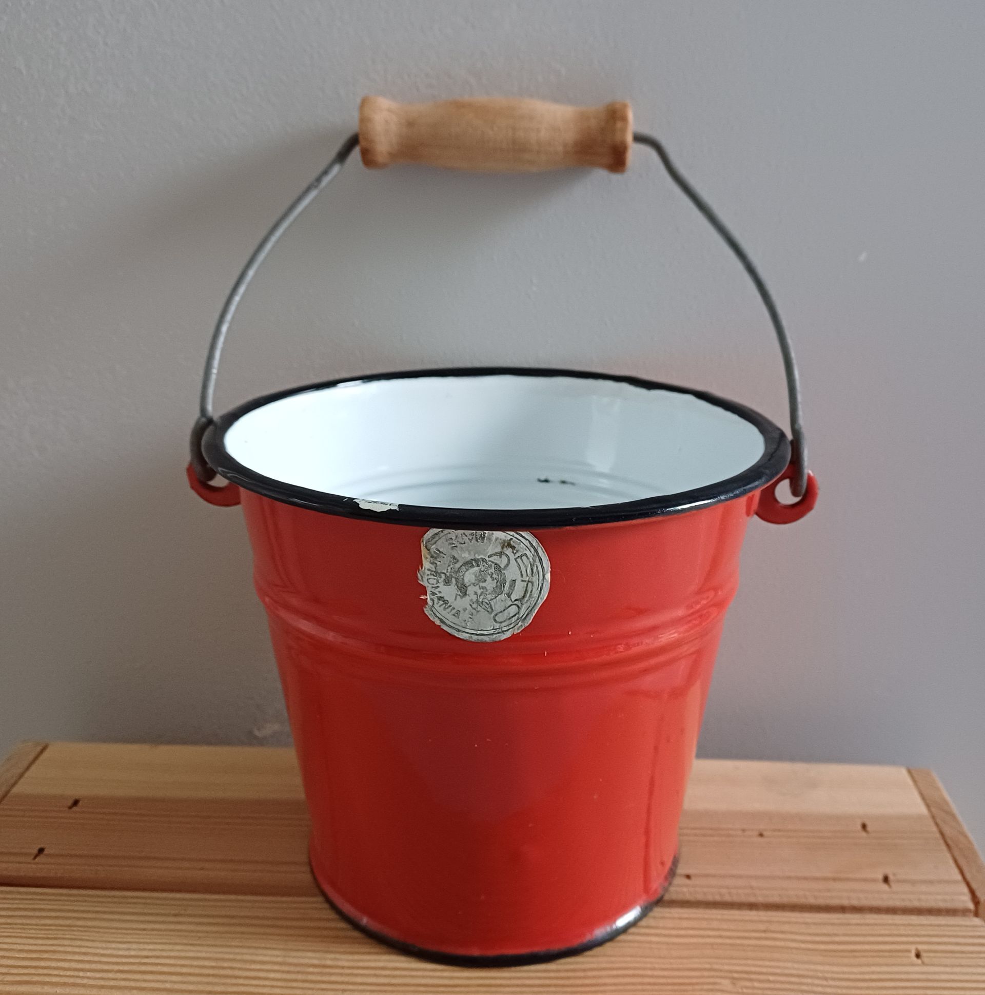 Rode emaille emmer met zwarte rand en een houten handvat van het merk ERO.