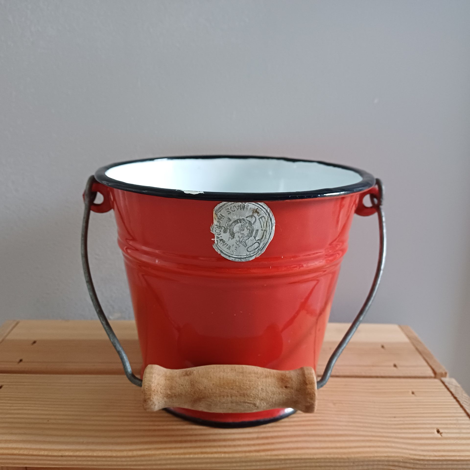 Rode emaille emmer met zwarte rand en een houten handvat van het merk ERO.