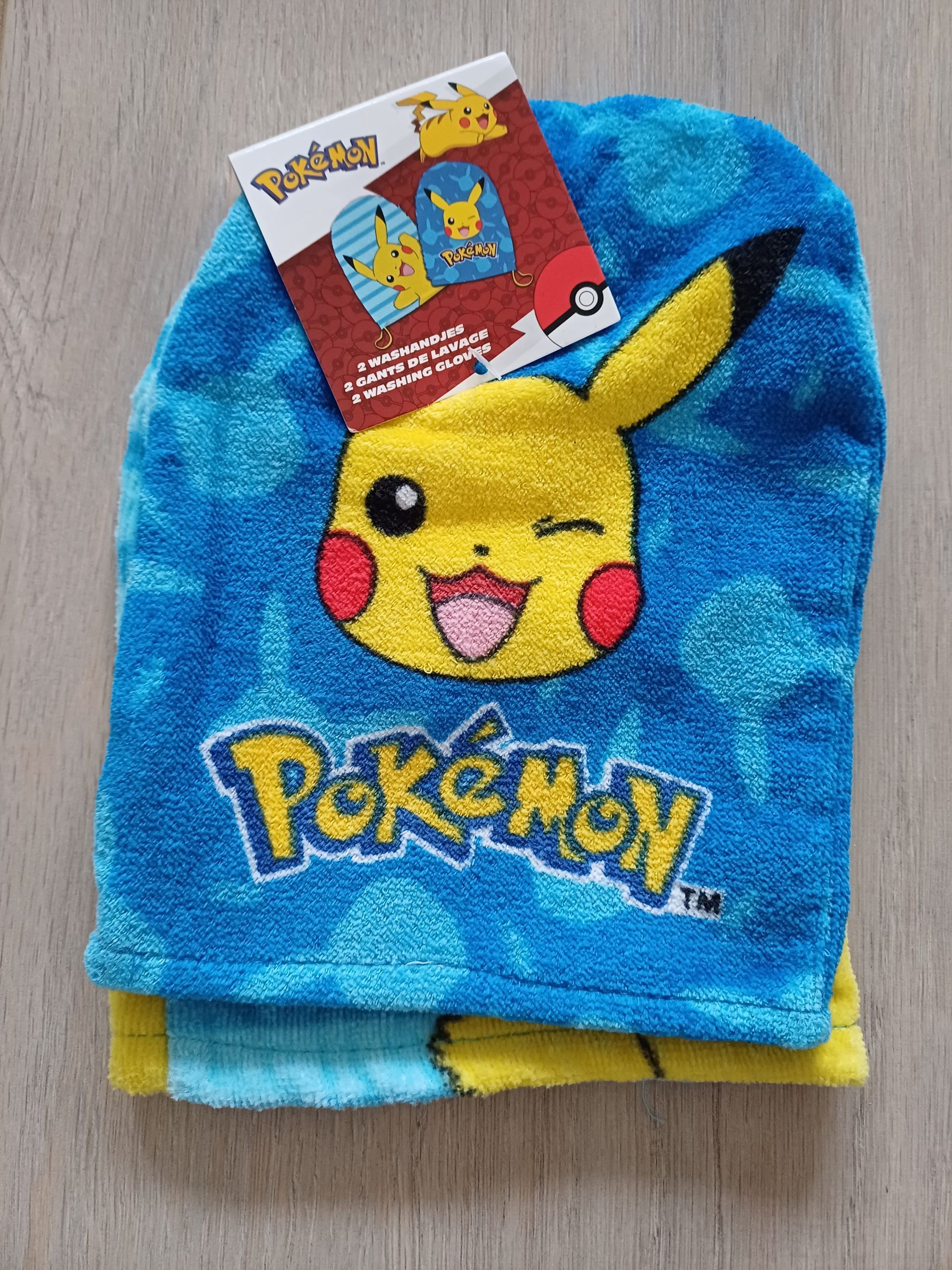 Blauw Pikachu-washandje met label, op houtnerf.