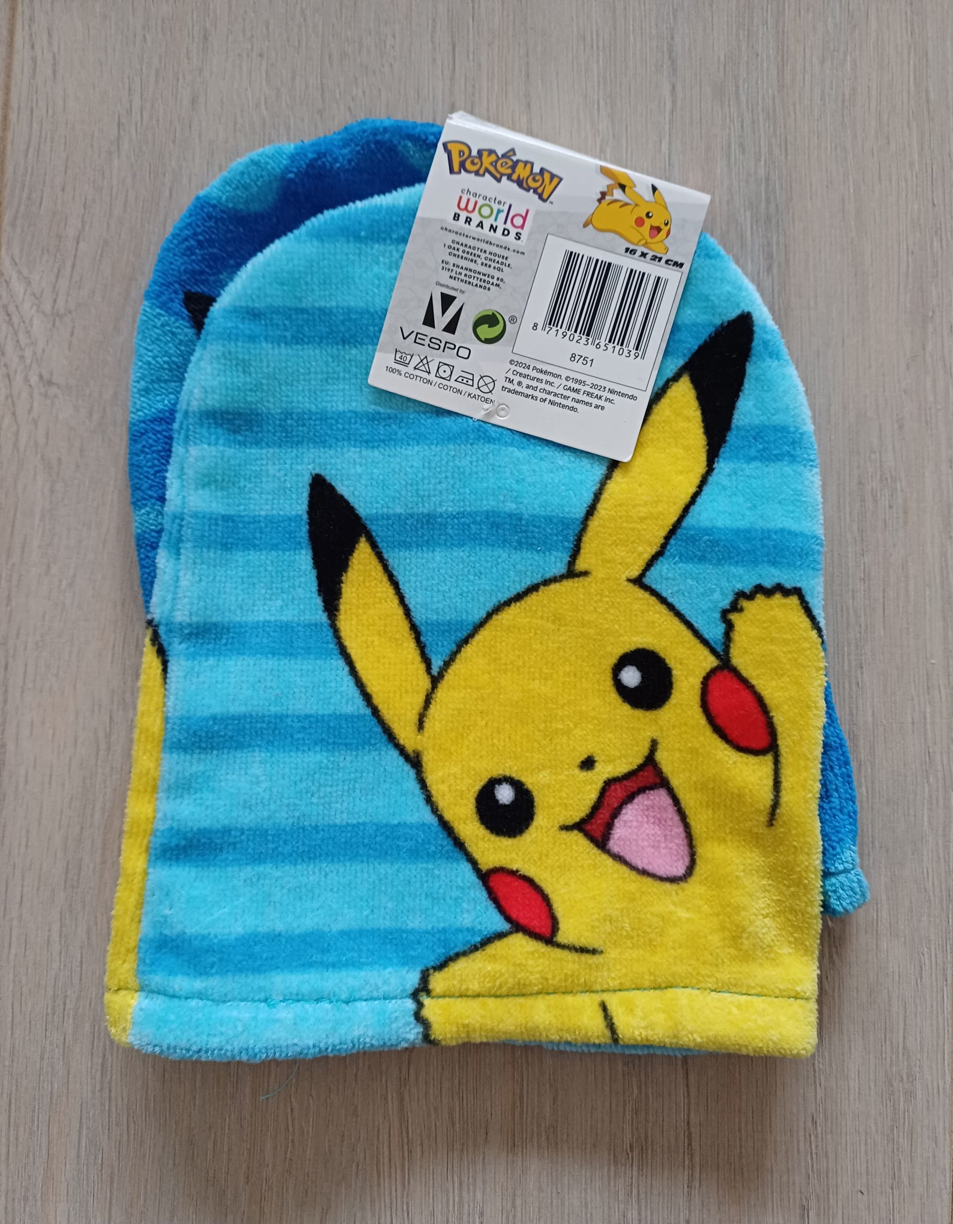 Blauw Pikachu-washandje met label, op houtnerf.