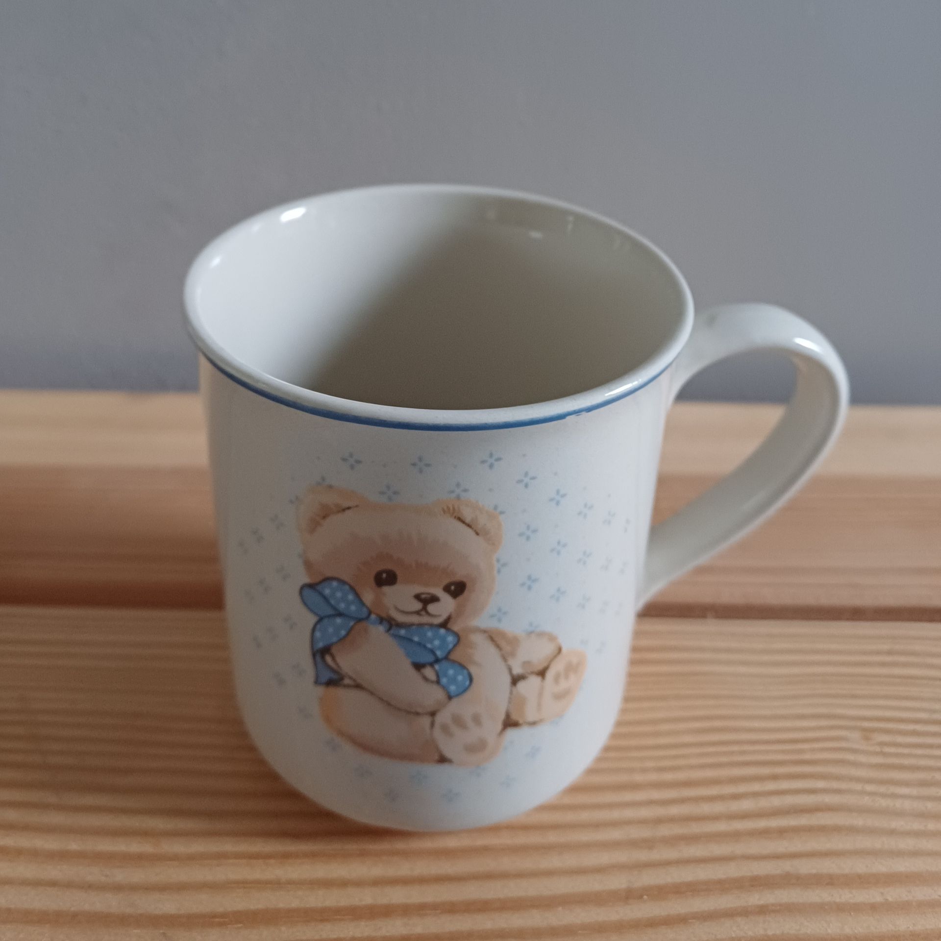 Witte keramische mok met teddybeerontwerp en blauwe accenten.
