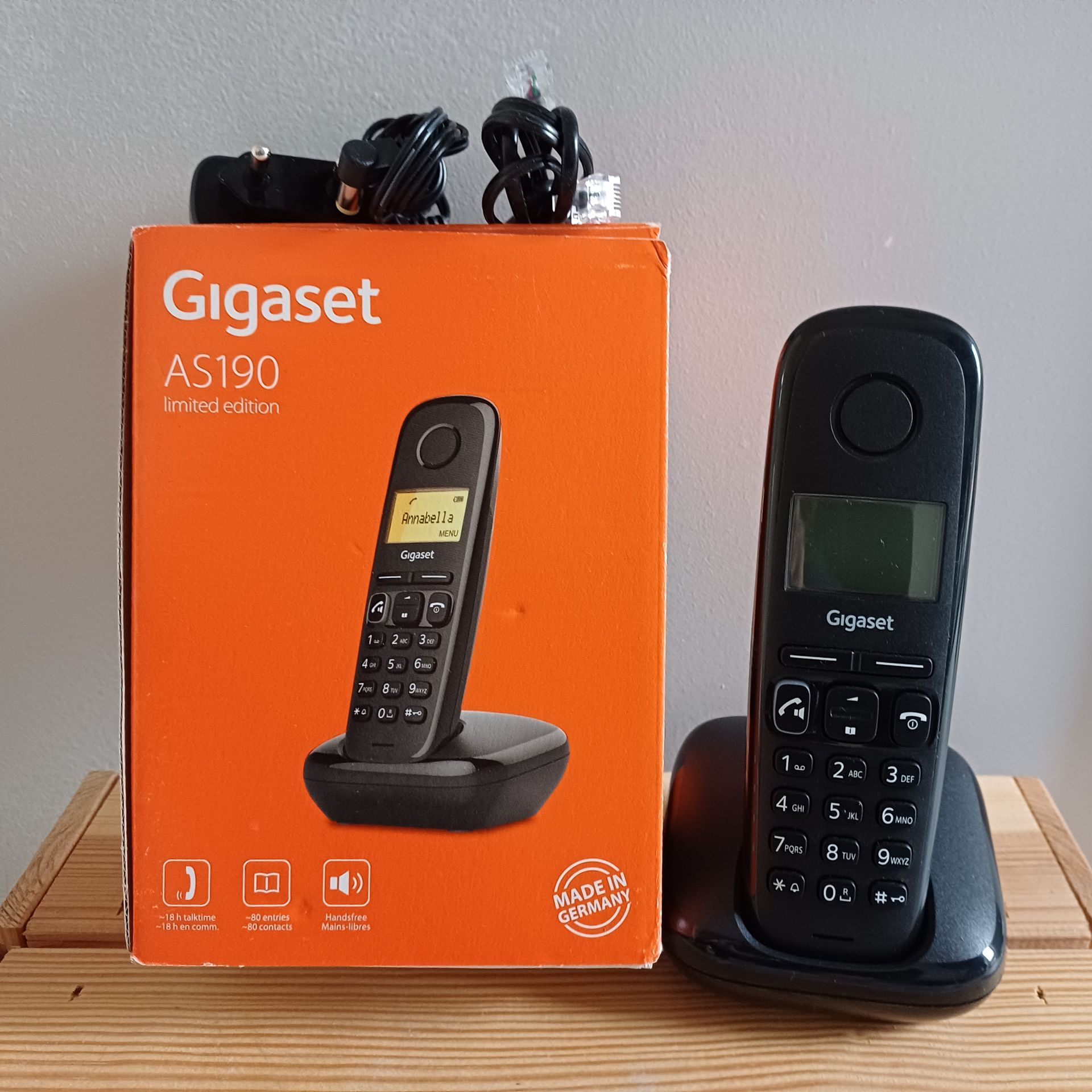 Gigaset AS190 draadloze telefoon in doos, zwarte handset op basisstation en twee oplaadkabels.