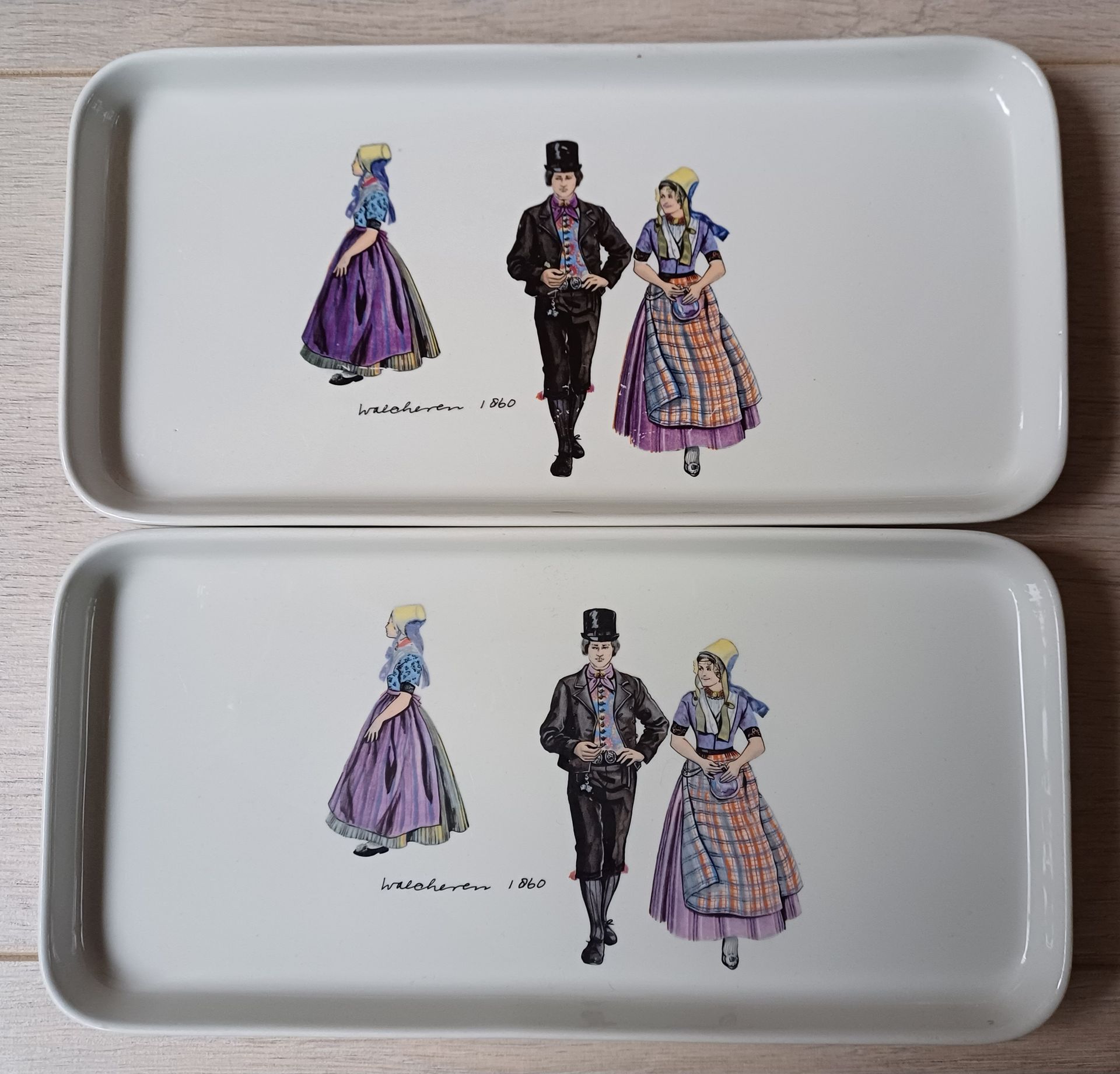 Twee witte rechthoekige dienbladen met afbeeldingen van traditionele volksdansers.