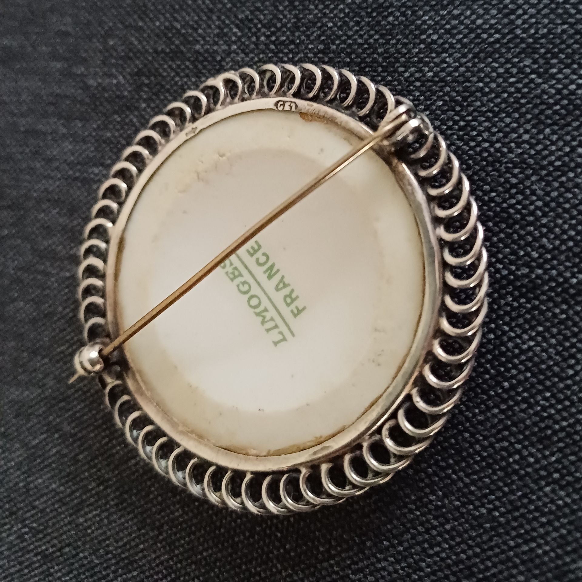 Antieke Limoges porseleinen ronde broche met geschilderd bloemmotief en een zilveren rand.
