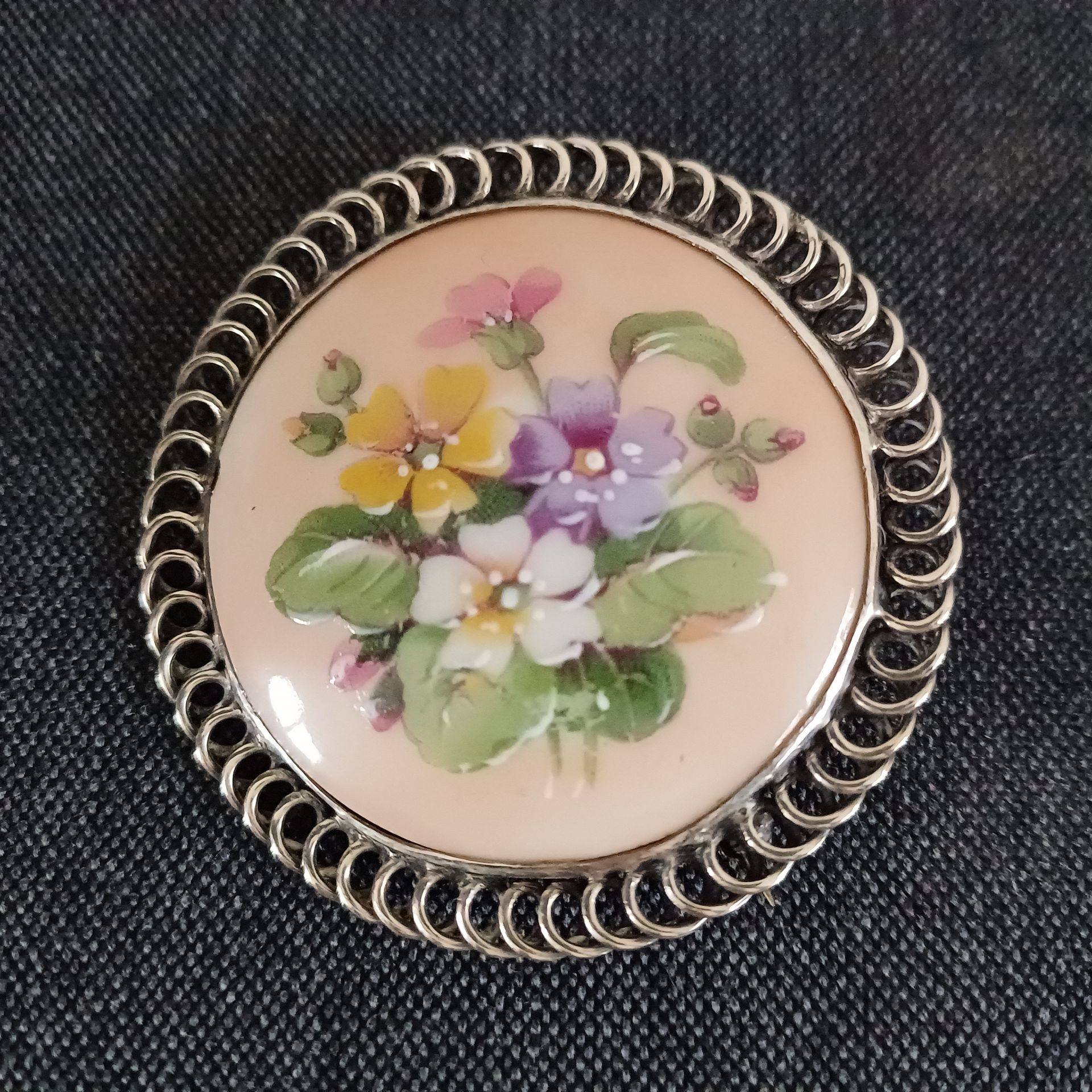 Antieke Limoges porseleinen ronde broche met geschilderd bloemmotief en een zilveren rand.