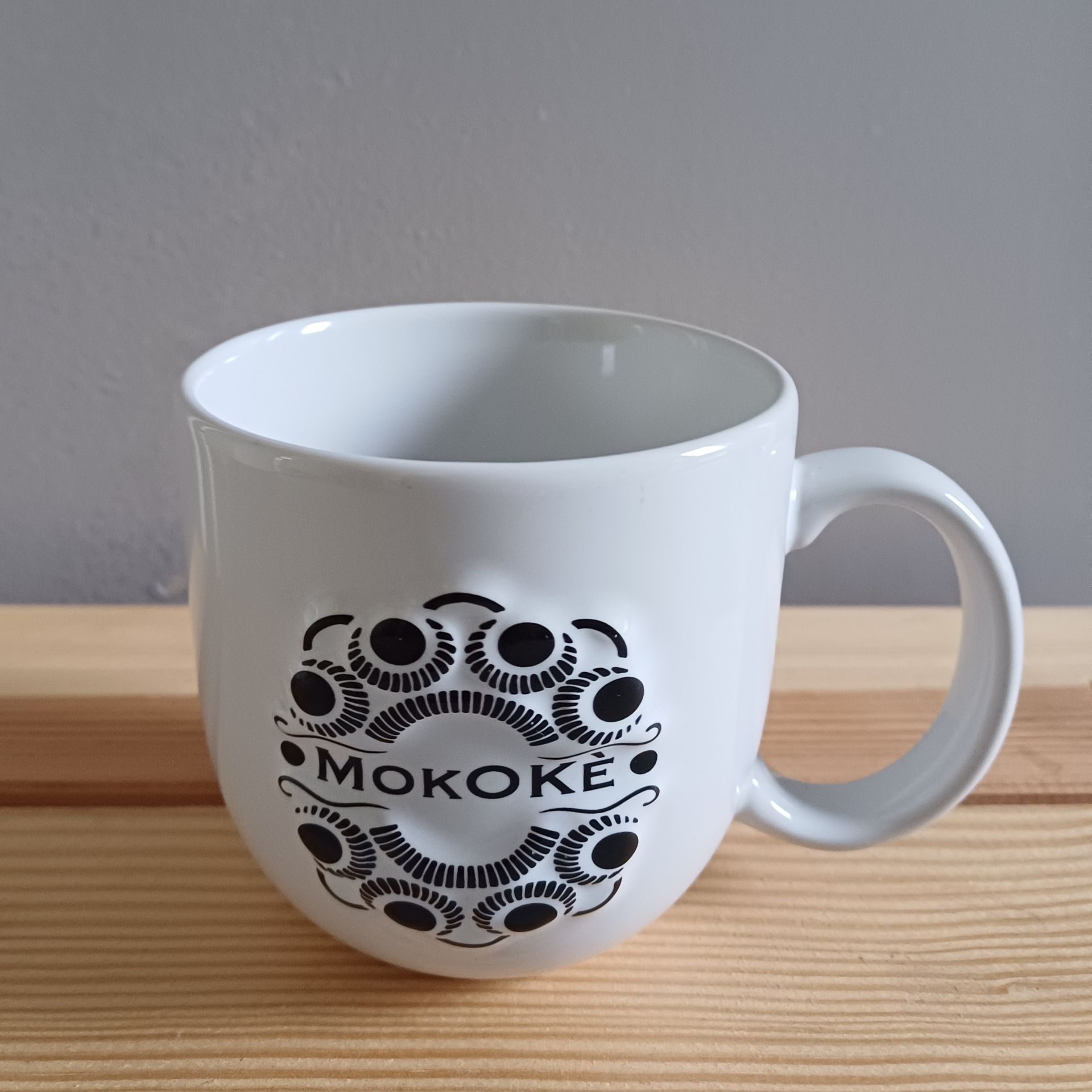 Witte mok met zwart decoratief ontwerp en het woord 
