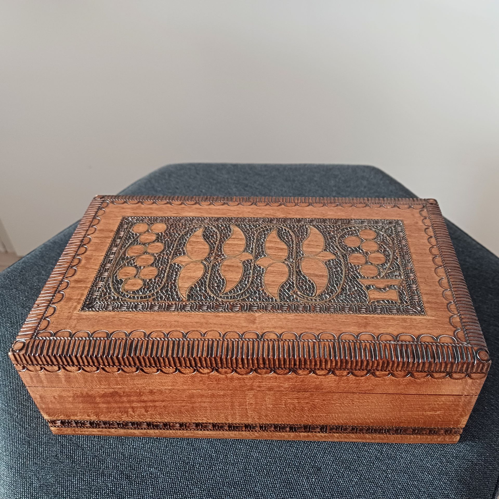 Houten doos met uitgesneden bloemmotief op een grijs oppervlak.