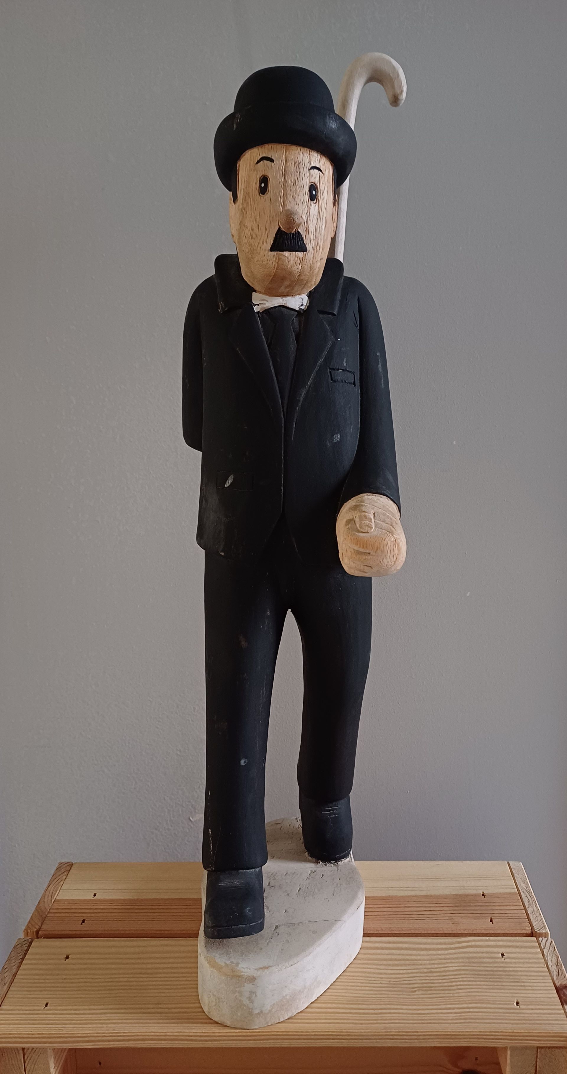 Houten beeld van Charlie Chaplin in een zwart pak, bolhoed en wandelstok.