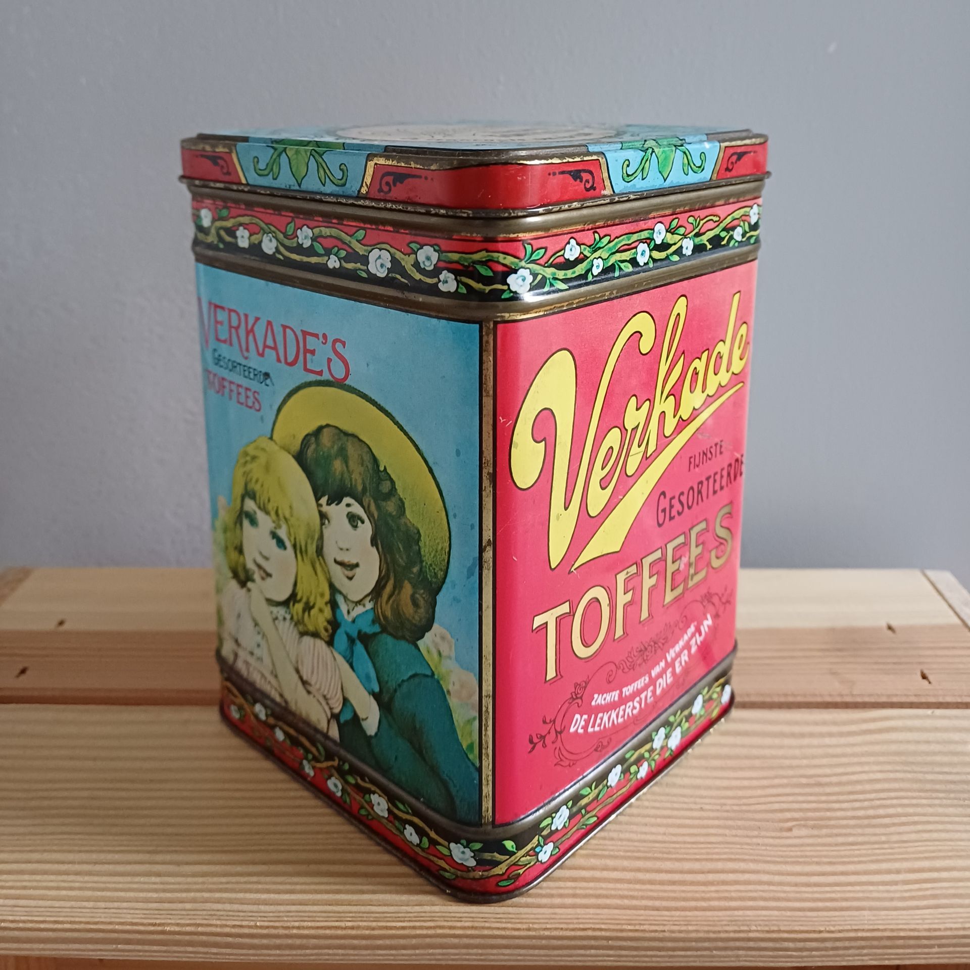 Antieke Verkade toffeeblik met afbeelding van twee vrouwen. Rood, blauw en geel met bloemmotief.