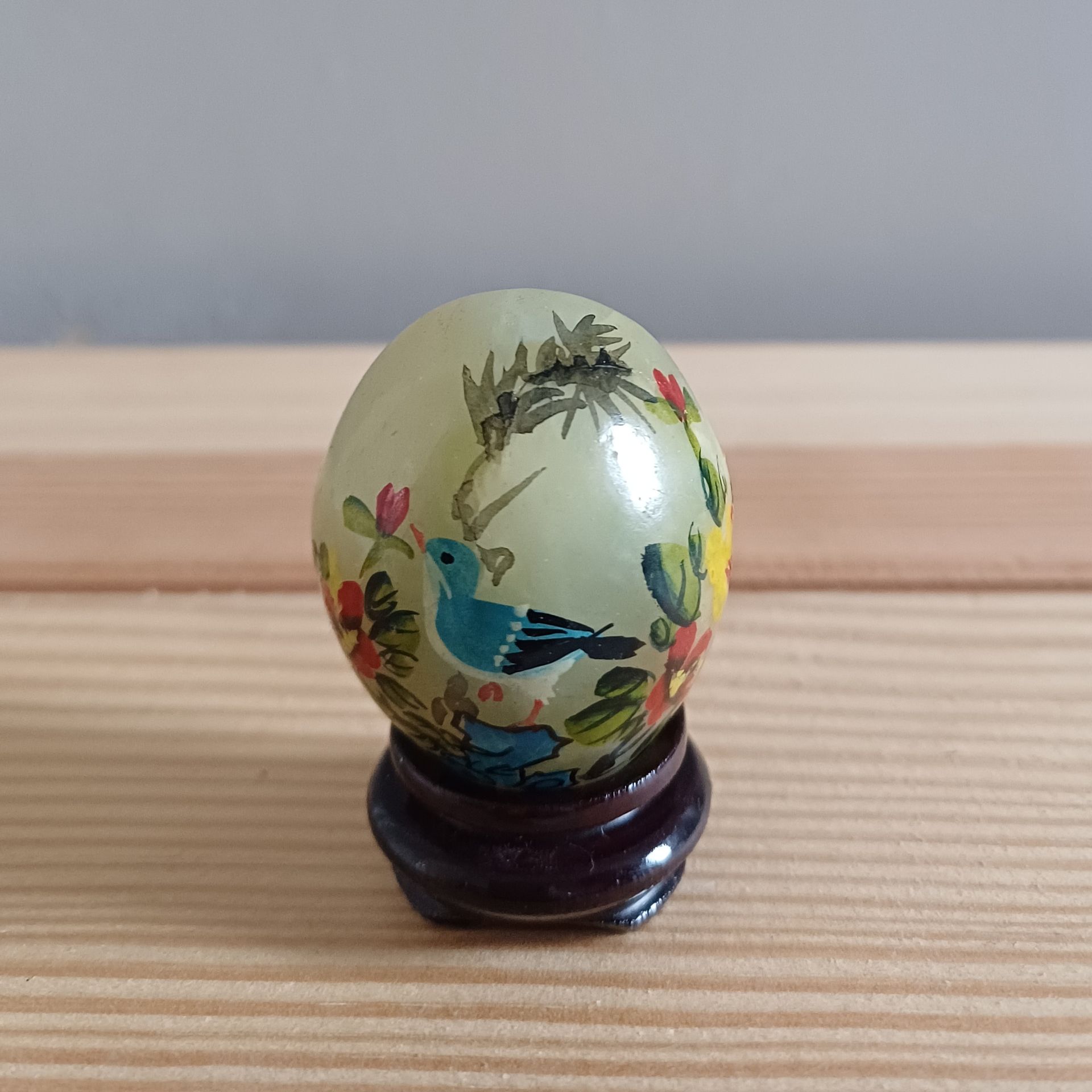 Decoratief Chinees  jade ei met beschilderde vogel- en bloemmotieven op houten voetjes.