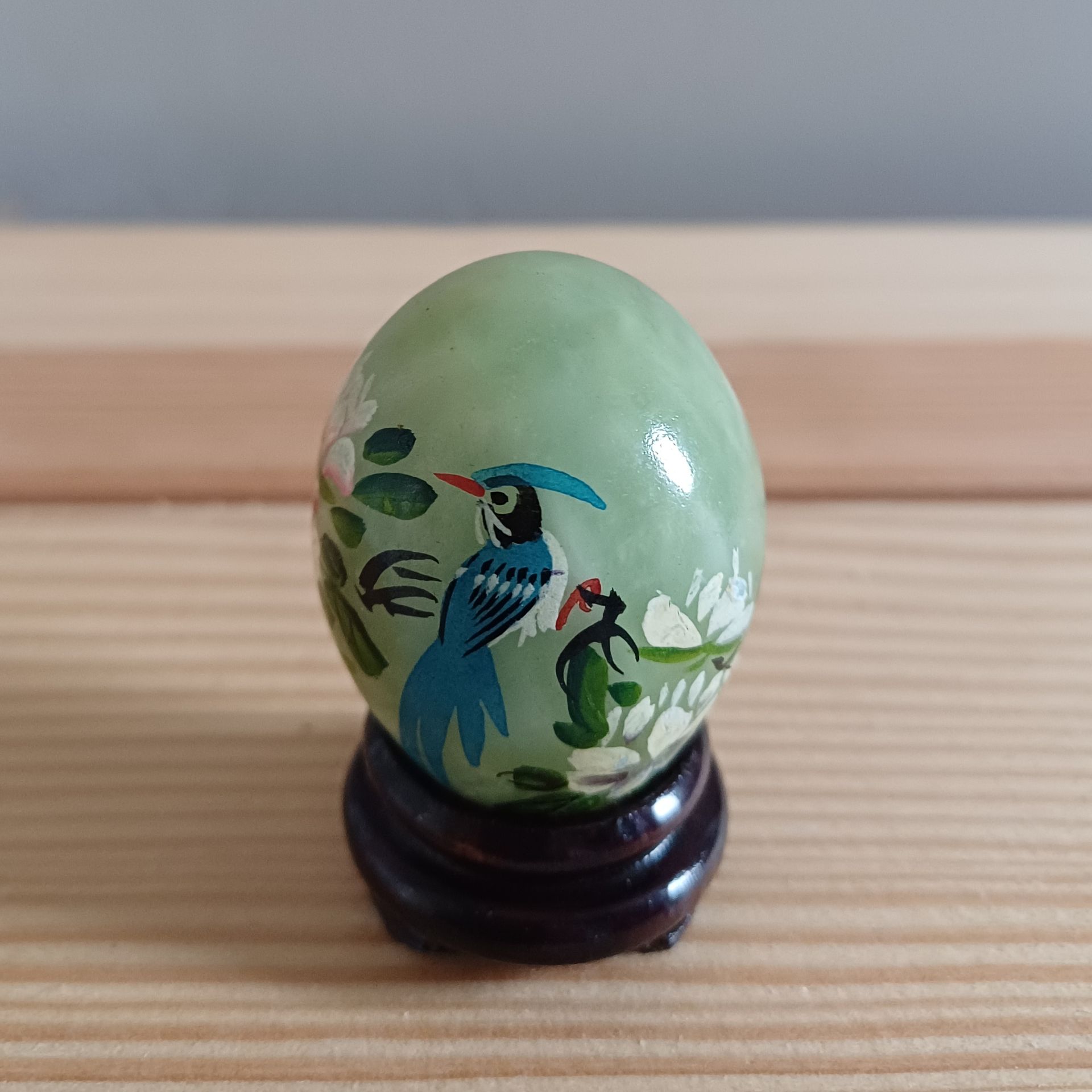 Decoratief Chinees  jade ei met beschilderde vogel- en bloemmotieven op houten voetjes.