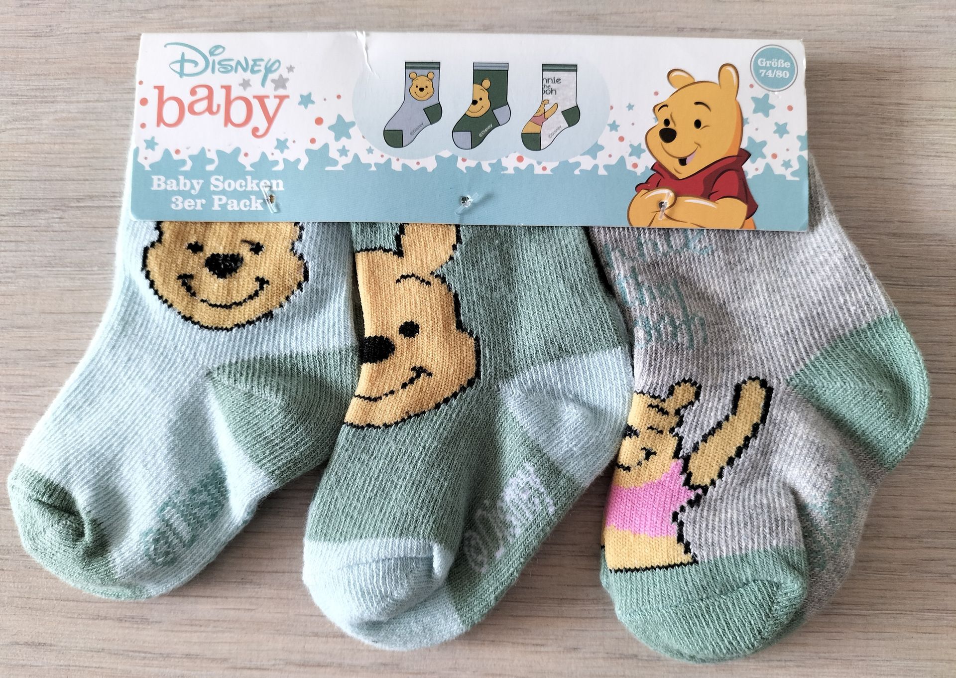 Drie Disney Baby Winnie de Pooh sokken in blauw, groen en grijs. Op de verpakking staat Winnie de Pooh afgebeeld.