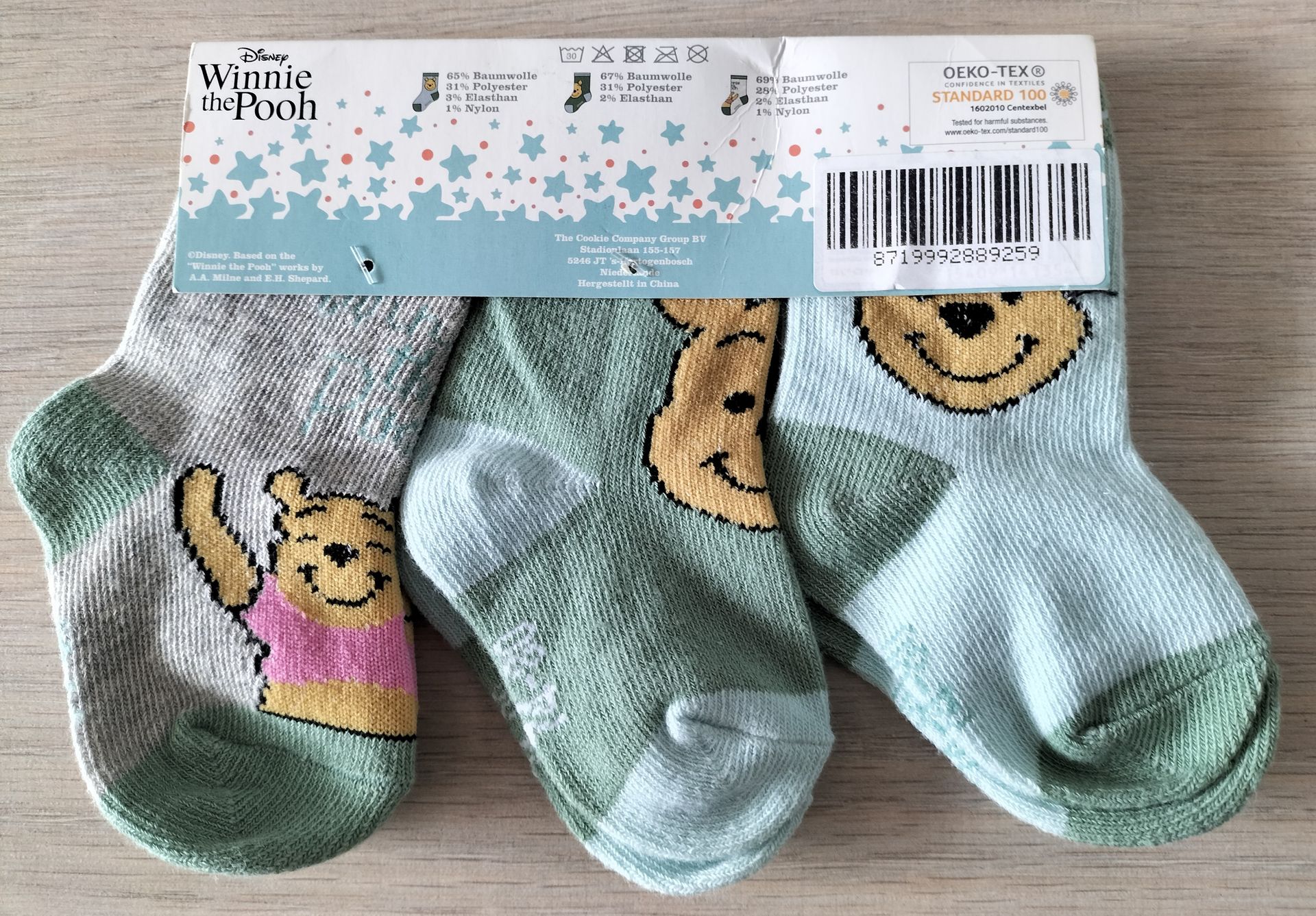 Drie Disney Baby Winnie de Pooh sokken in blauw, groen en grijs. Op de verpakking staat Winnie de Pooh afgebeeld.