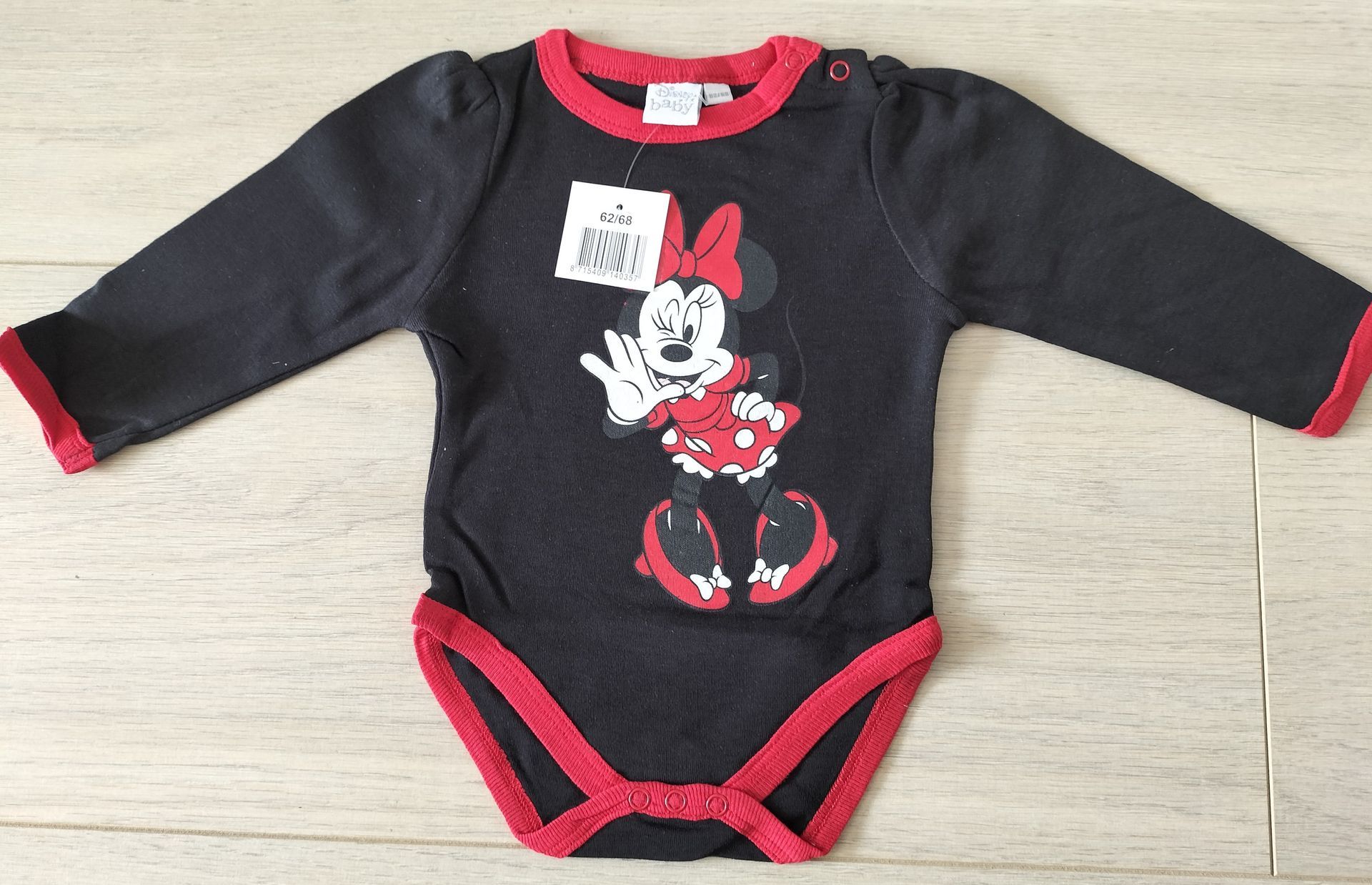 Zwarte Minnie Mouse babyromper met rode bies en label.
