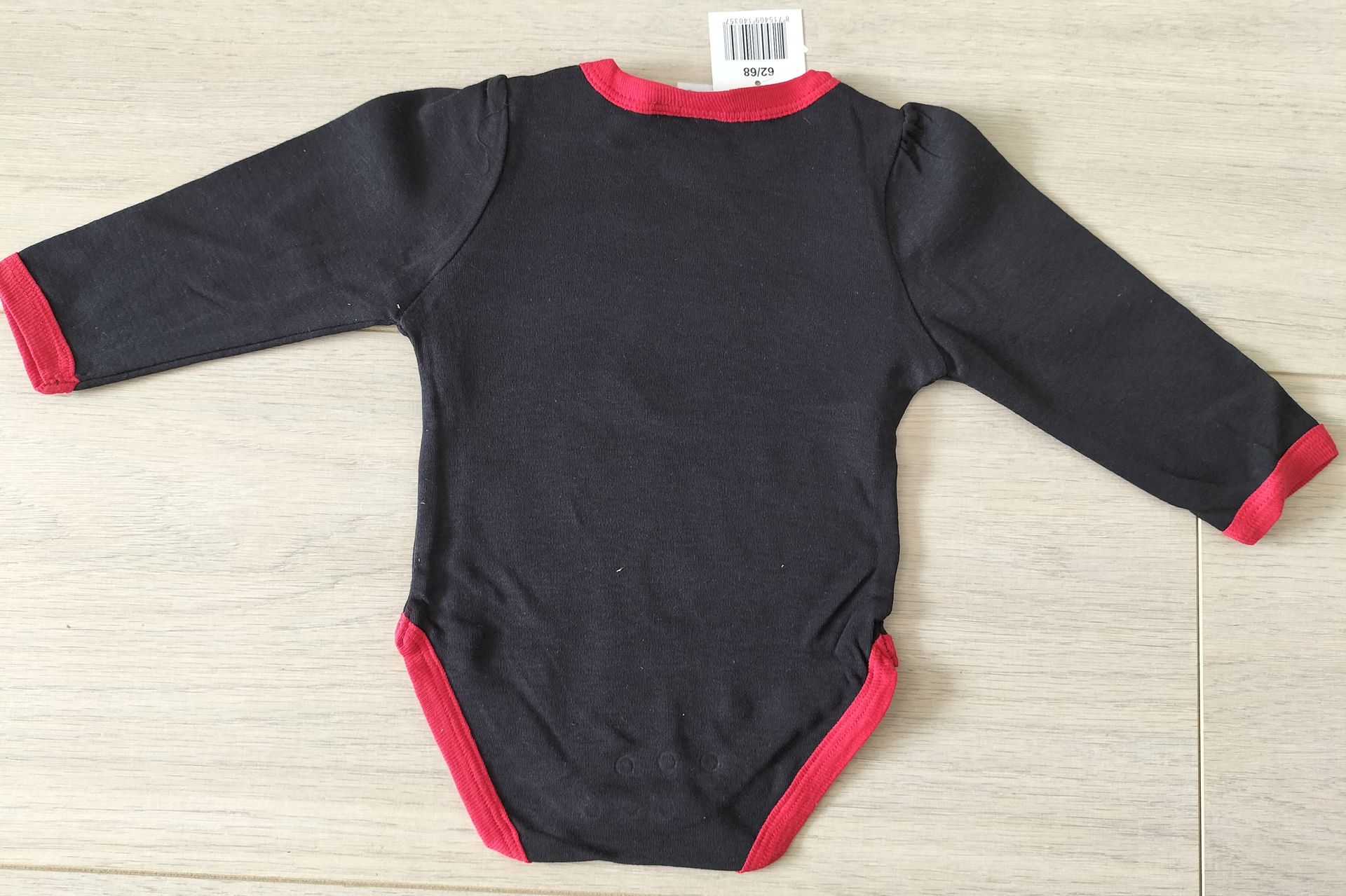 Zwarte Minnie Mouse babyromper met rode bies en label.