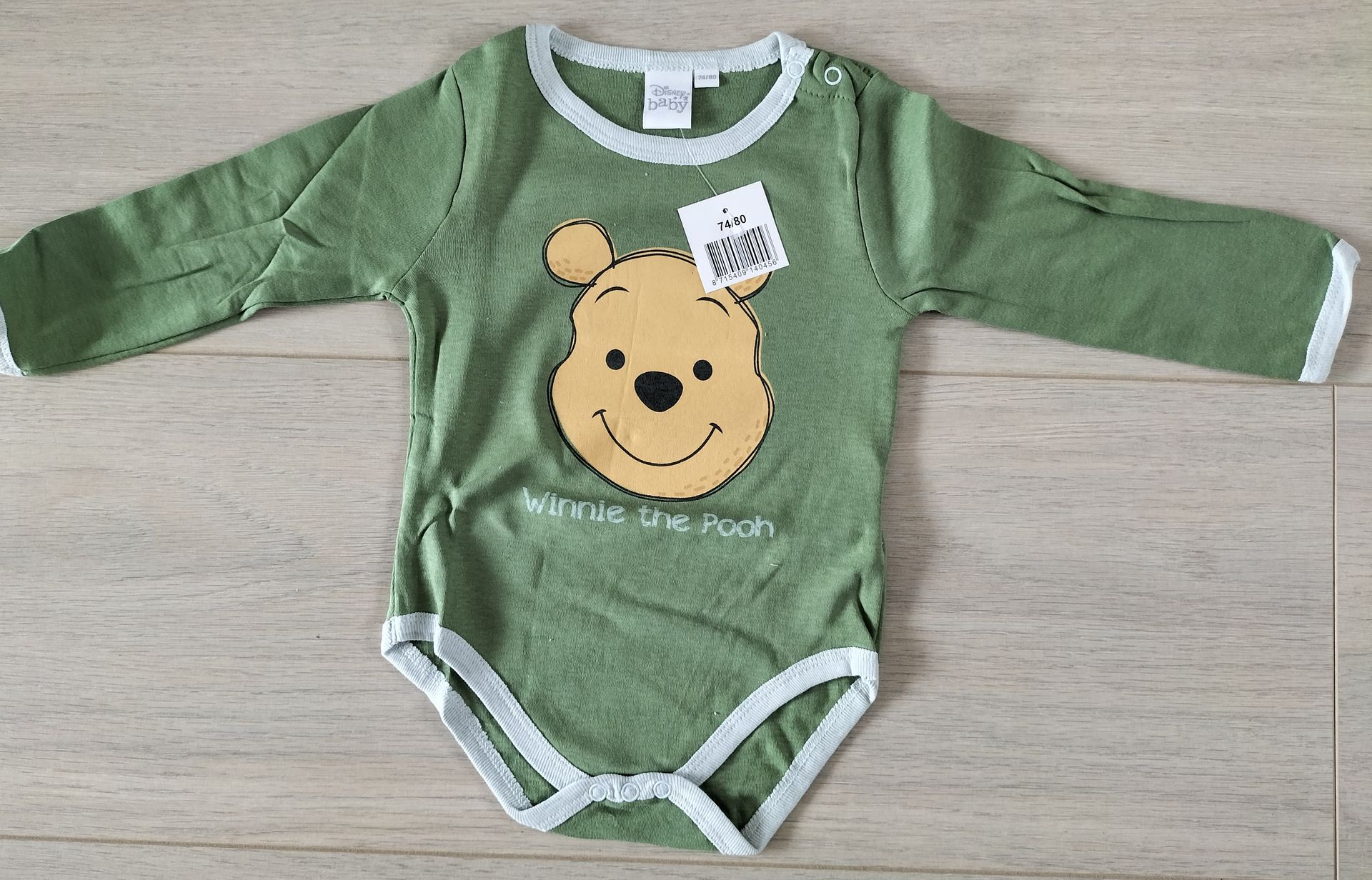Groene Winnie de Pooh babyromper met witte bies.