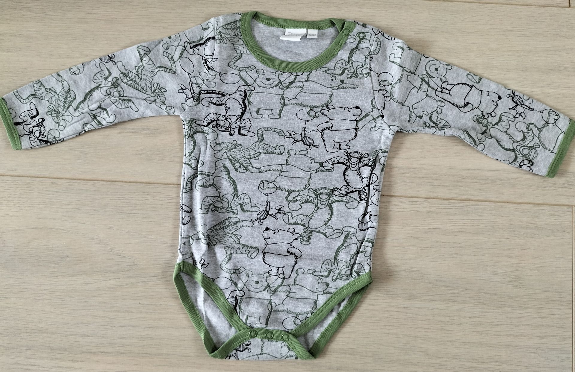 Grijze en groene babyromper met een patroon, plat neergelegd.