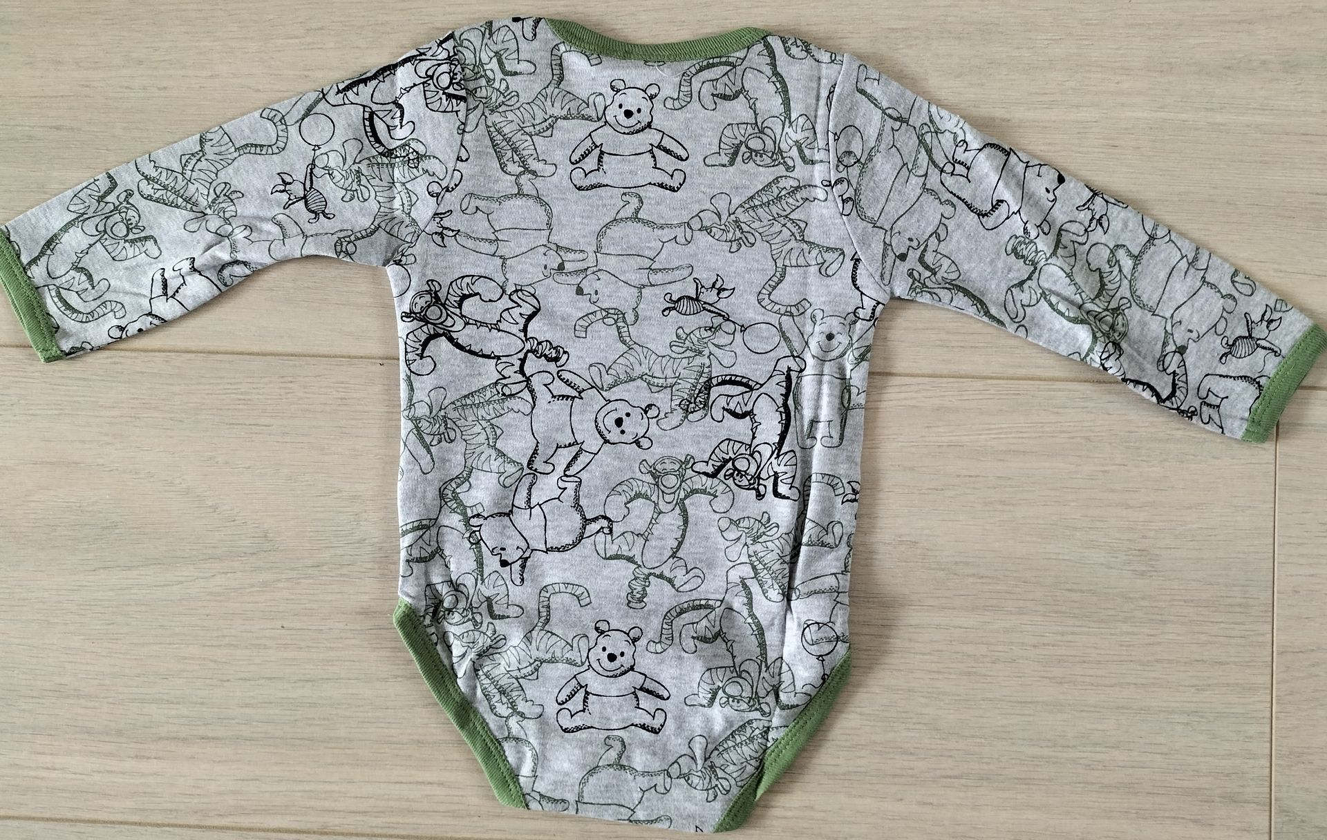 Grijze en groene babyromper met een patroon, plat neergelegd.