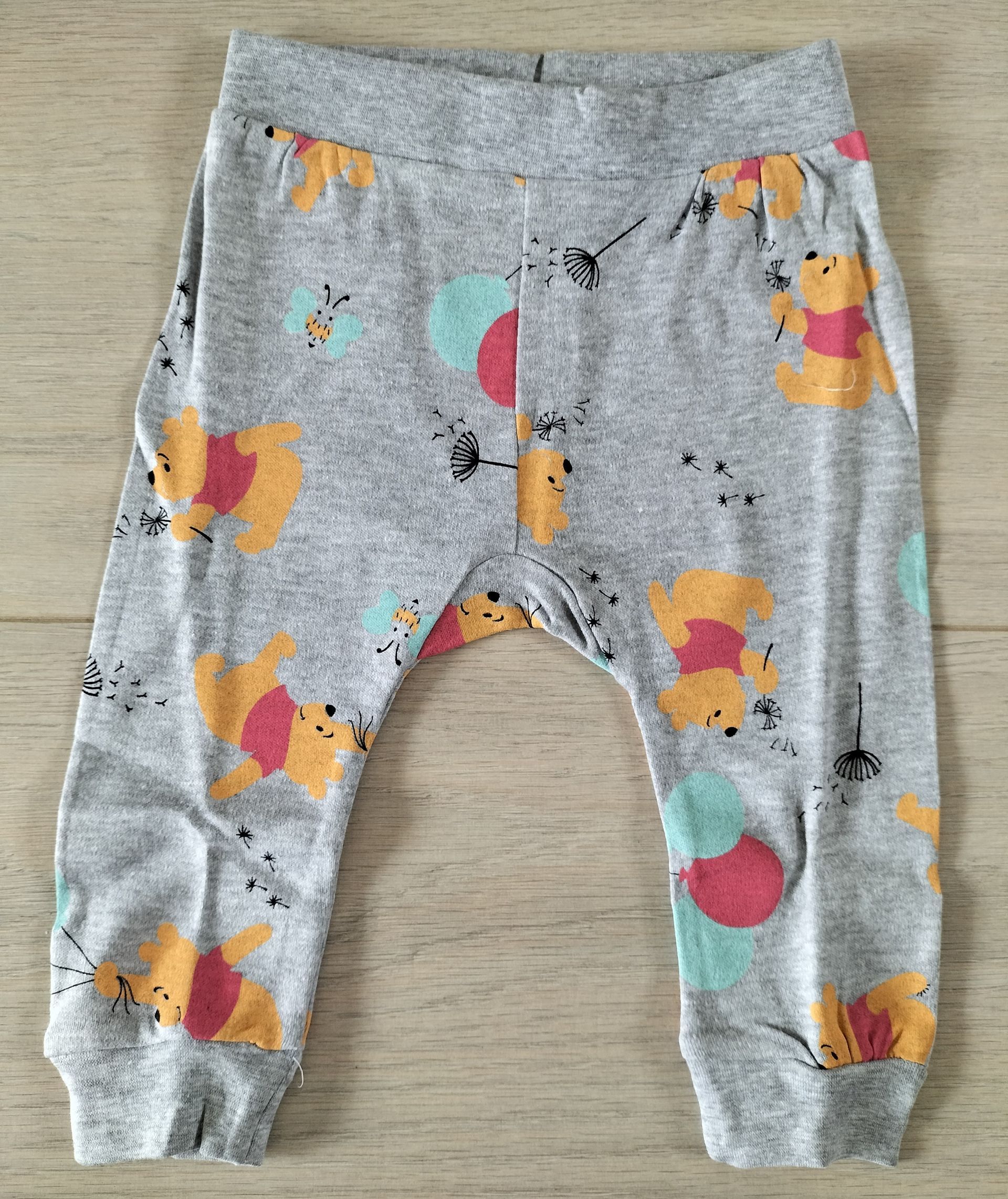 Grijze babybroek met Winnie de Winnie de Pooh en spetters in aquarel-stijl.