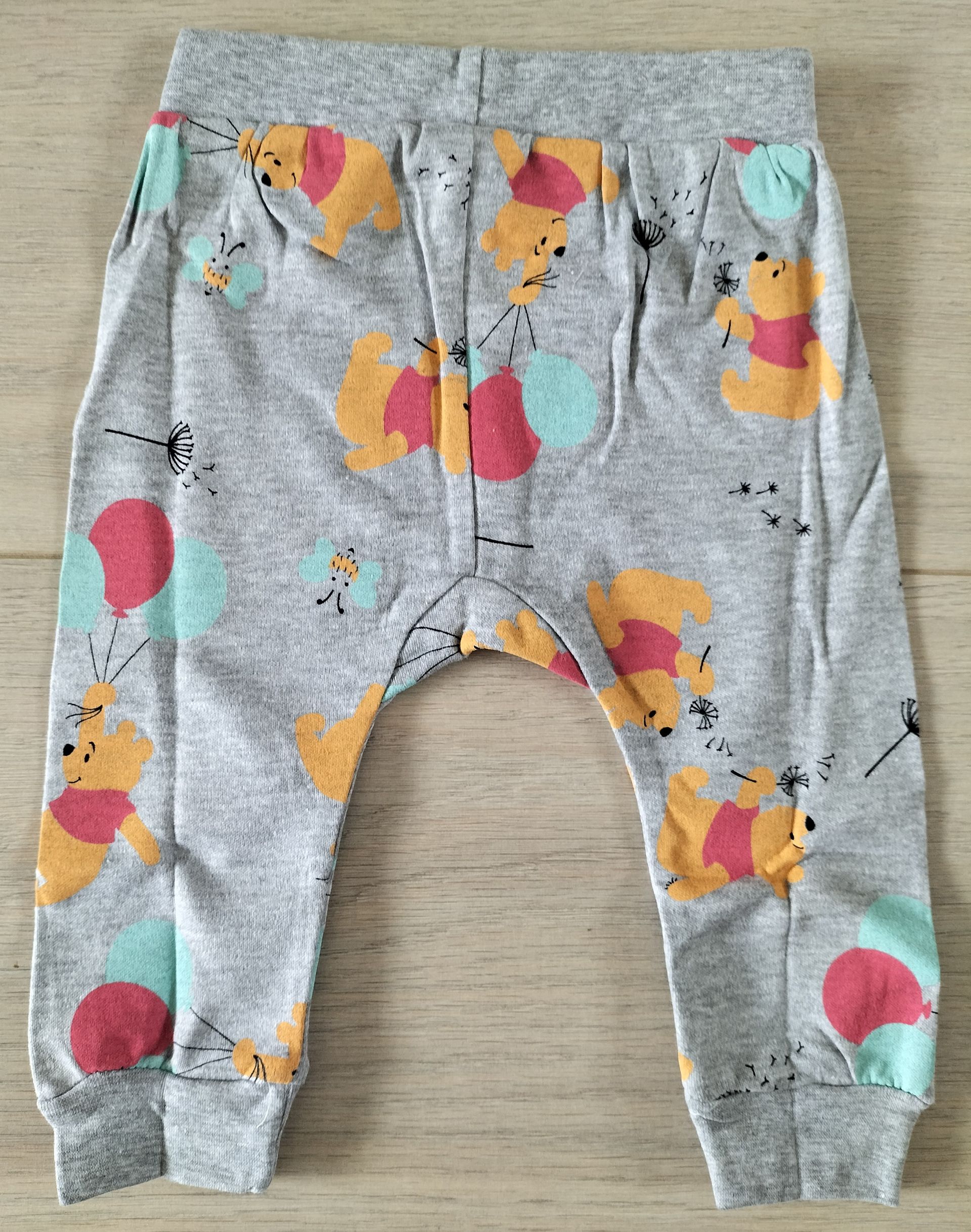 Grijze babybroek met Winnie de Winnie de Pooh en spetters in aquarel-stijl.