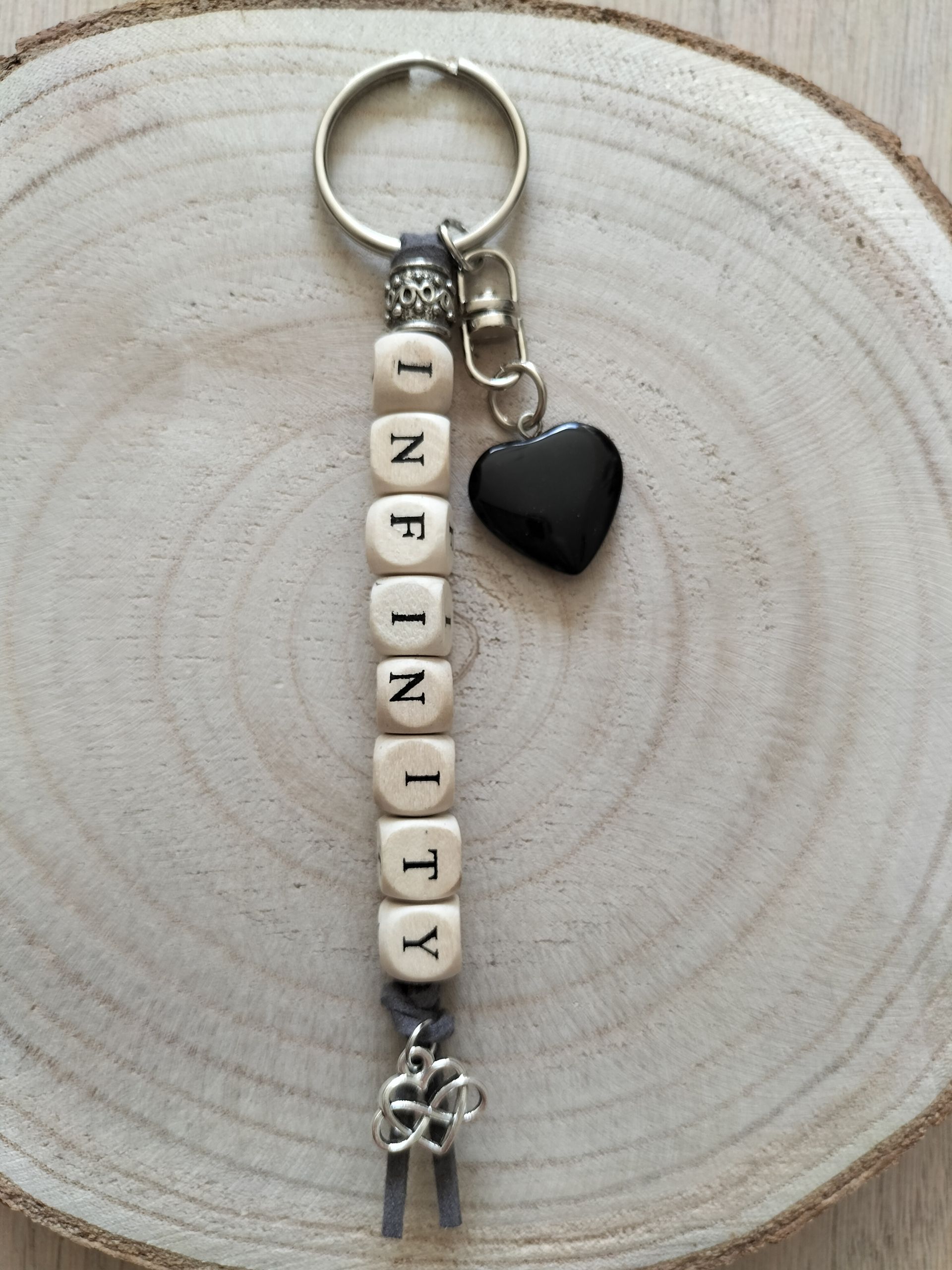 Sleutelhanger met houten kralen die het woord "INFINITY" vormen en een odsidiaan hartje en Keltisch infinity bedeltje.